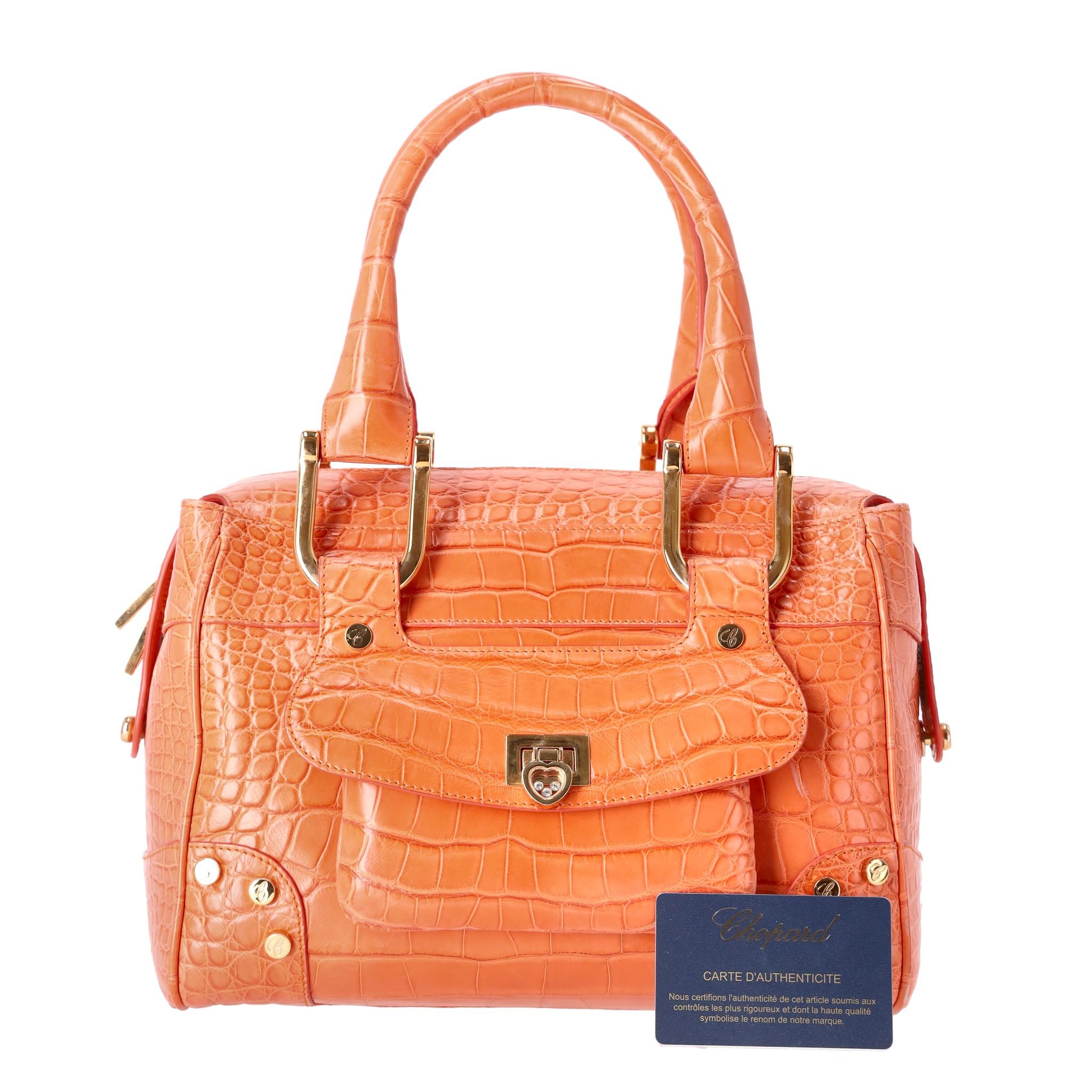 Rare Item - Chopard Crocodile Skin Carolina Bag

Ltd edition - Orange exotic skin bag with top carry/should handles and gold hardware.

Love heart closure with floating crystals to the front feature pocket.

Zipper closure to the bags  main