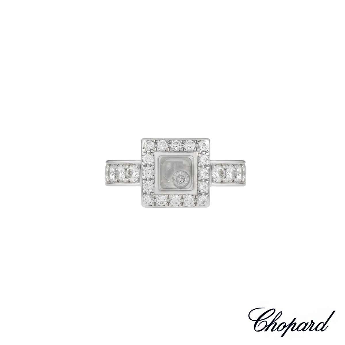 A stylish Chopard 18k white gold diamond set ring from the Happy Diamonds Collection. The ring has a single freely moving round brilliant cut diamond encased behind the Chopard signed glass, totalling 0.05ct. The ring has a further 24 round