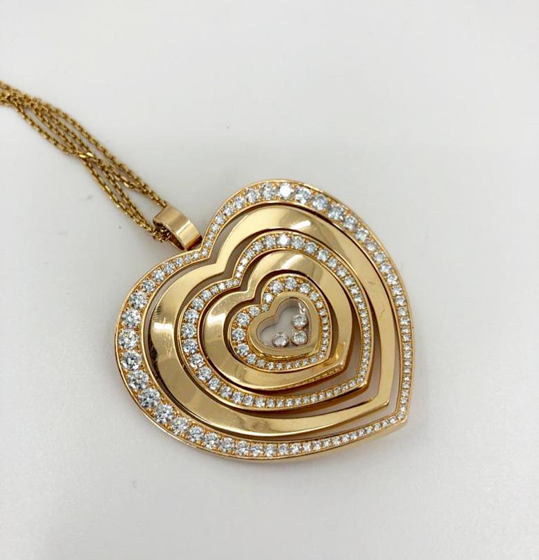 An elegant diamond heart pendant by Chopard in 18k gold; designed as a stylized heart comprised of 5 articulated sections, alternating between pave-set diamond, and smooth gold, with a miniature heart-shaped enclosed centre containing three loose