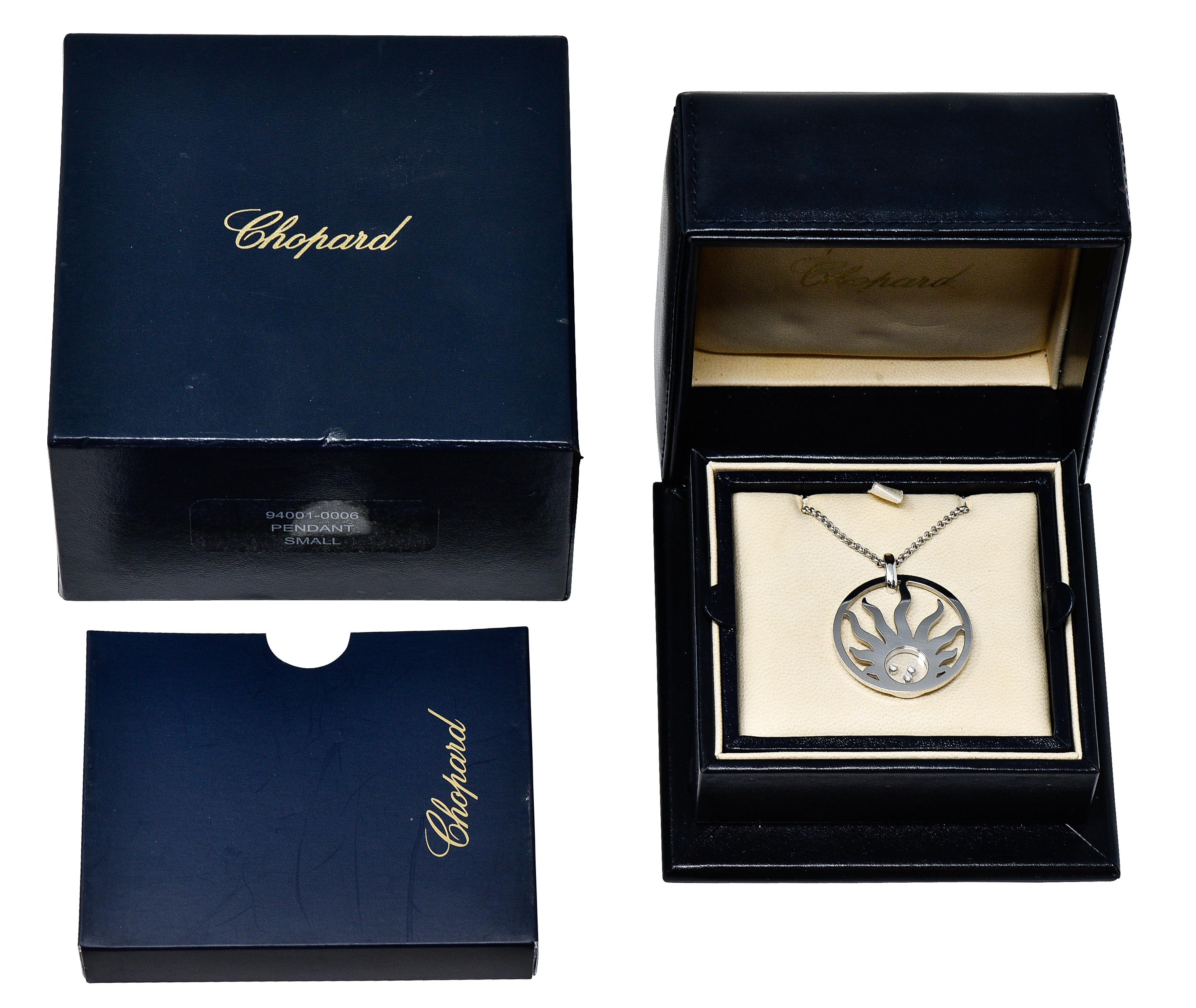 Rolo chain necklace suspends a substantial circular pendant

Pierced with a stylized sun motif while centering a circular opening covered by glass

Inscribed Chopard while encasing three free floating and bezel set 