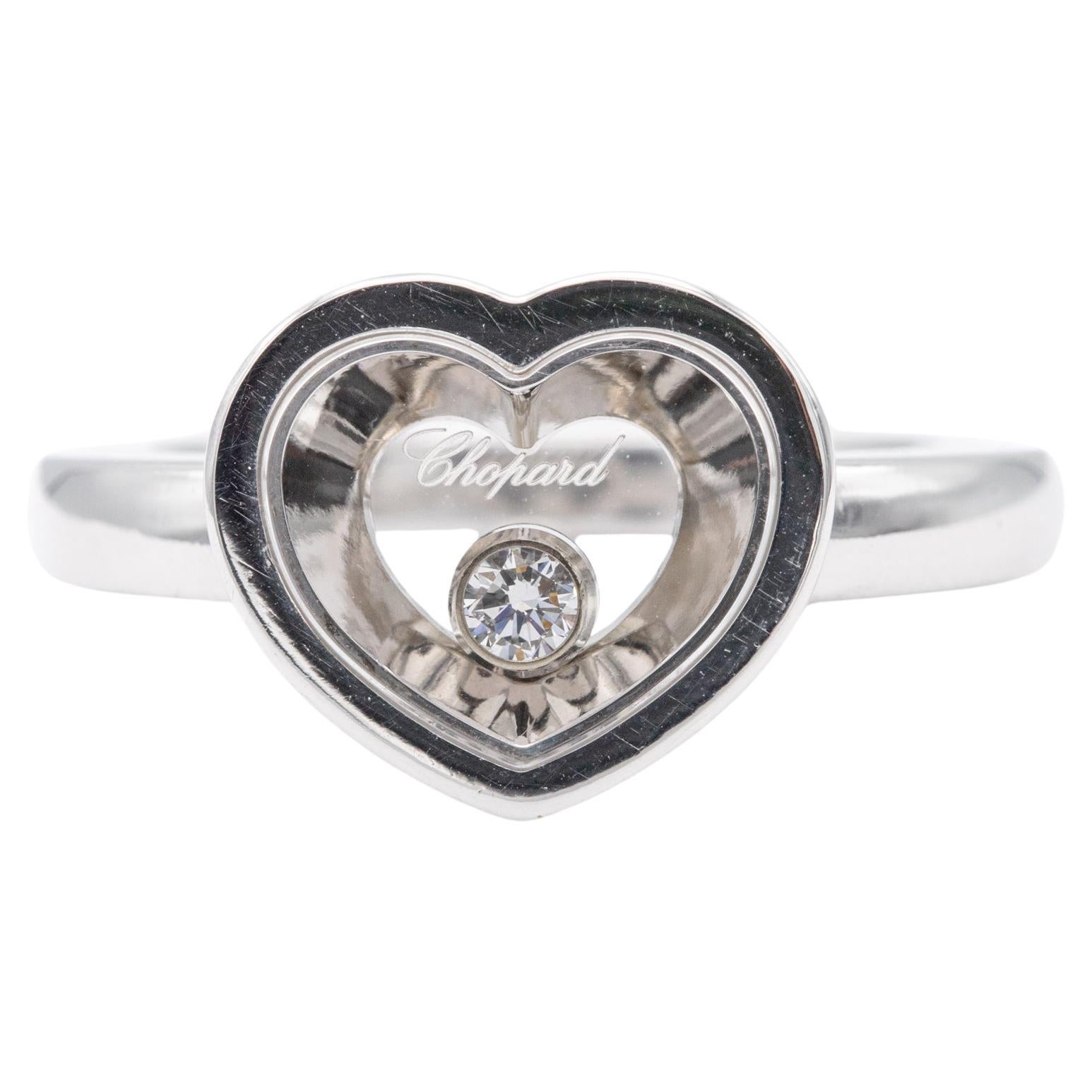Zum Verkauf steht dieser wunderschöne und zeitlose Chopard Ring. Dieser herzförmige Ring ist aus Chopards 'Happy Diamonds' Collection. Dieser Ring aus 18-karätigem Weißgold trägt einen Diamanten im Brillantschliff, der zwischen zwei Kristallgläsern