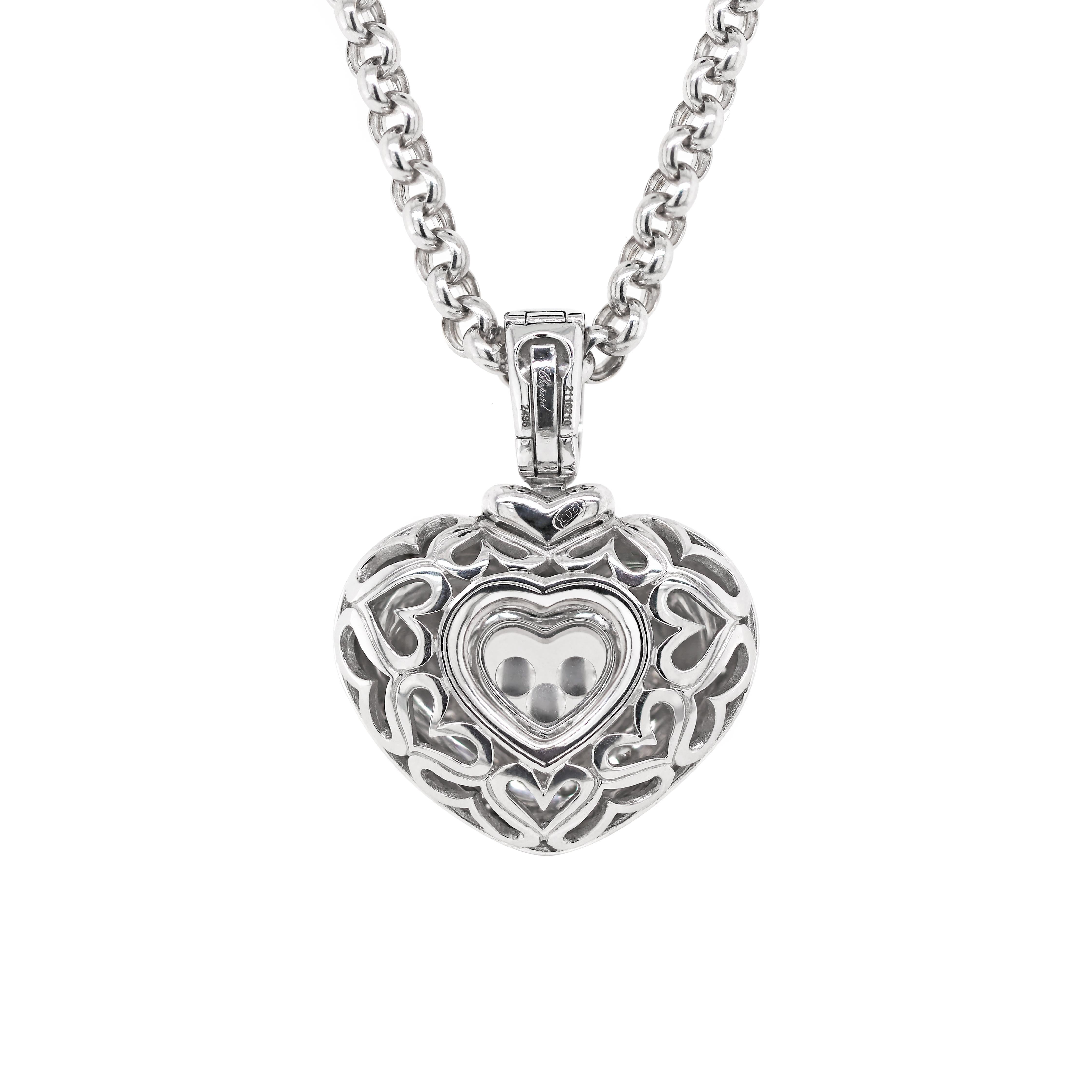 This amazing 18ct white gold pendant from Chopard's signature Happy Diamond collection features a heart shaped hollow mount. The front of the pendant is fitted with a cluster of 27 rubover set round brilliant cut diamonds, totalling to an