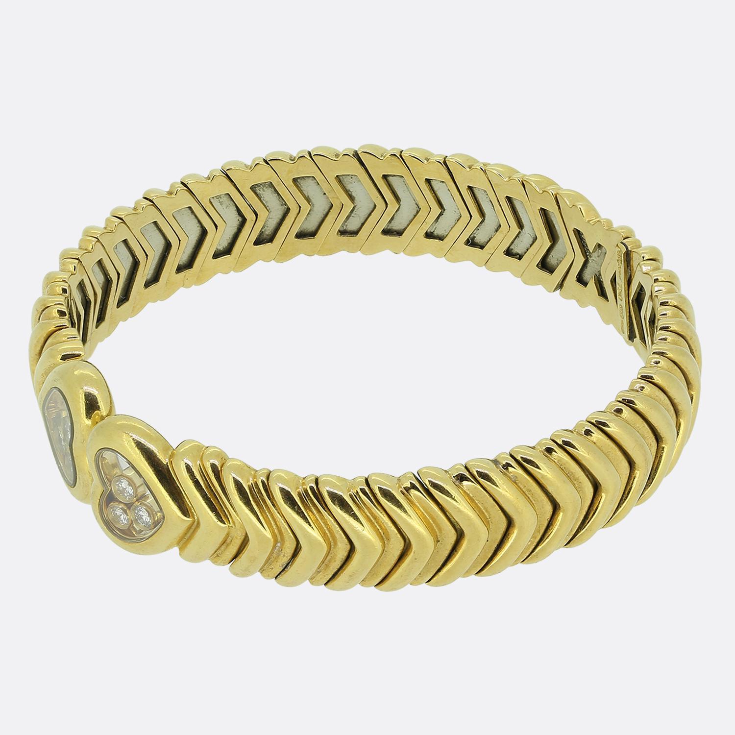 Voici un bracelet en or jaune 18 ct du célèbre joaillier français Chopard. Cette pièce élégante est ornée d'une large bande superposée qui s'enroule autour du poignet en forme de couple. Chaque extrémité du bracelet se termine par un trio de joyeux