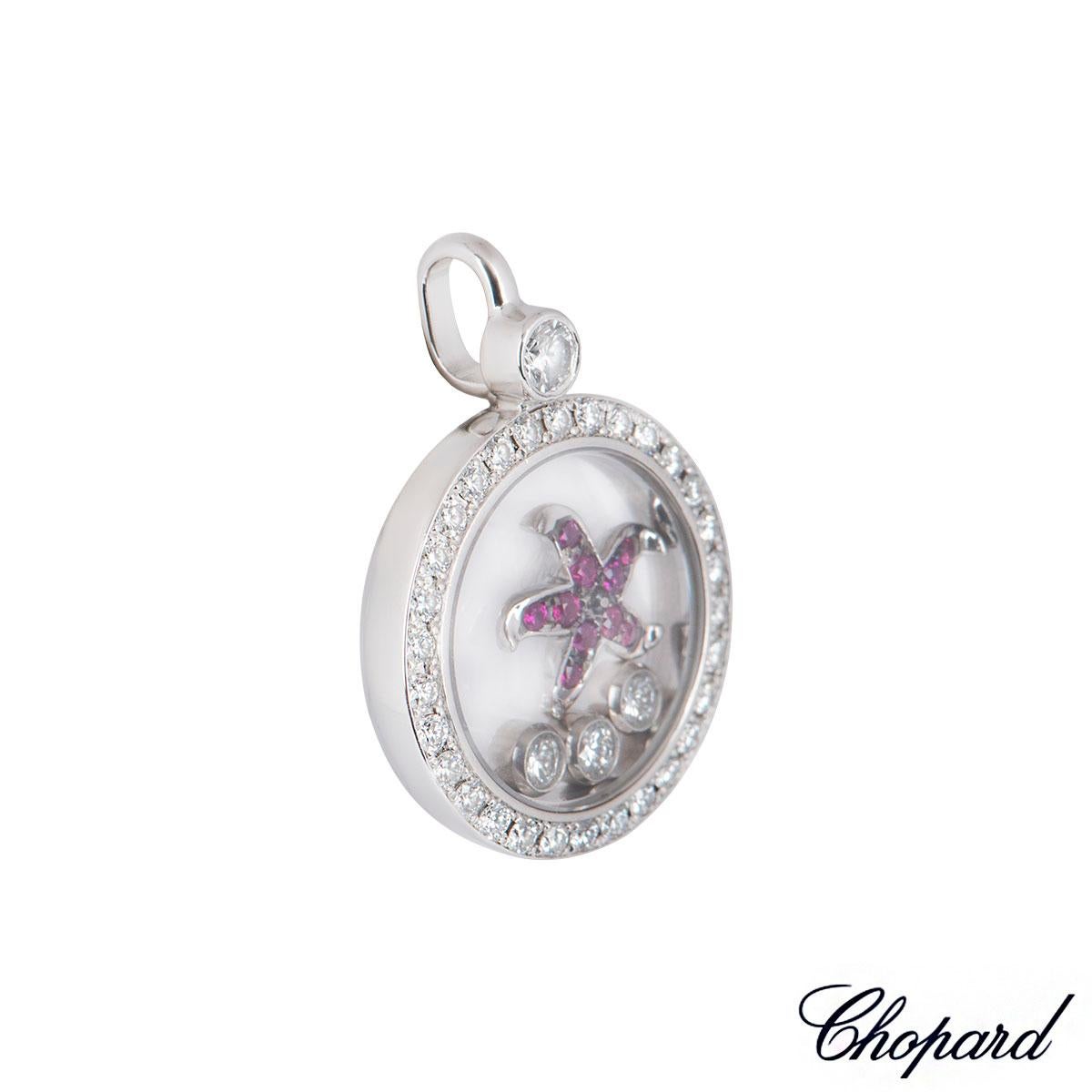 An 18k white gold diamond and ruby pendant by Chopard from the Happy Diamonds collection. The pendant features a pave set bezel with round brilliant cut diamonds and 3 floating diamonds with a ruby set starfish encased behind the iconic Chopard