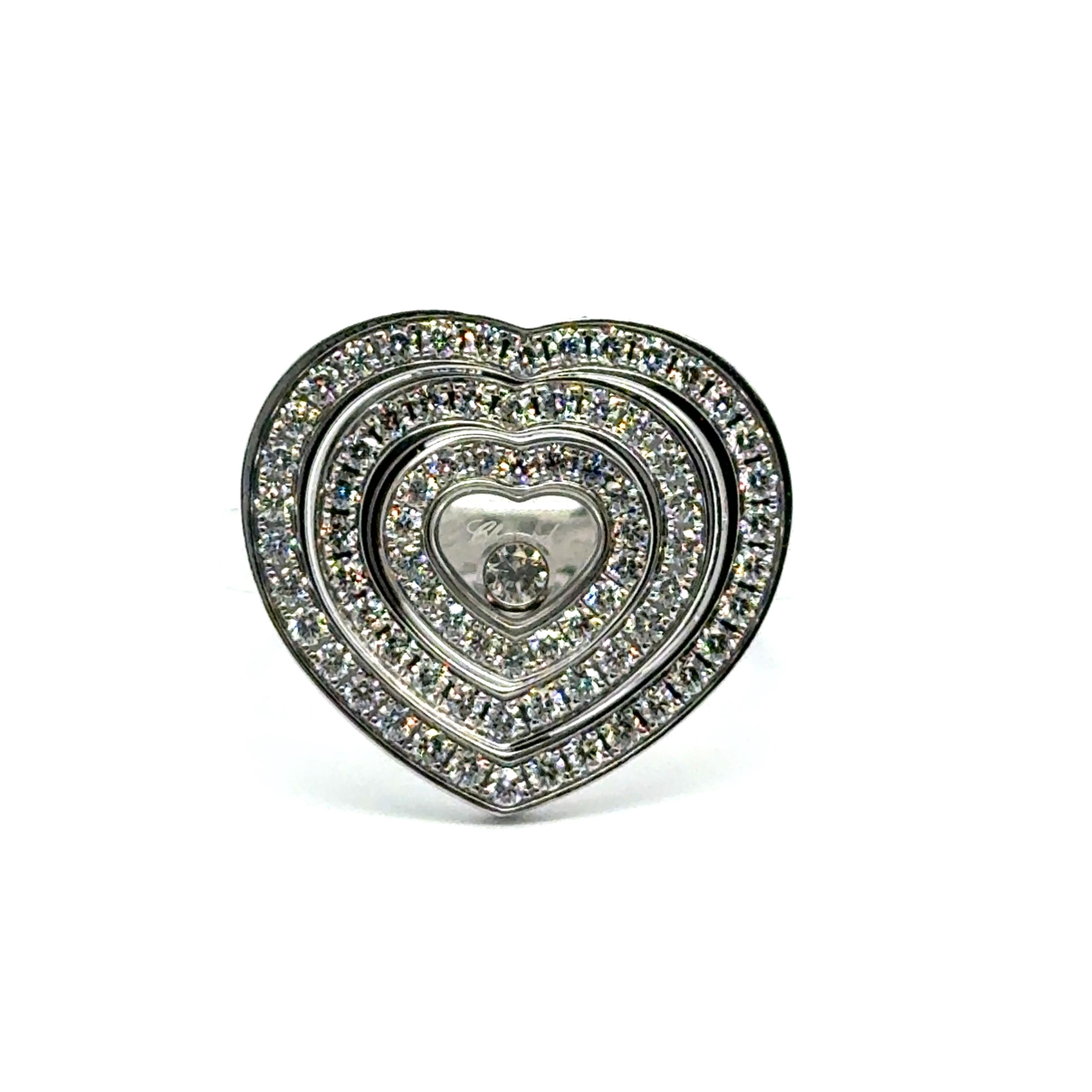 Dieser zarte und zugleich strahlende Ring von Chopard ist aus 18 Karat Weißgold gefertigt und hat die Form eines anmutigen Herzmotivs. In seinem Zentrum liegt ein einzelner Brillant von 0,05 Karat, der von 76 kleineren Brillanten von insgesamt 0,55
