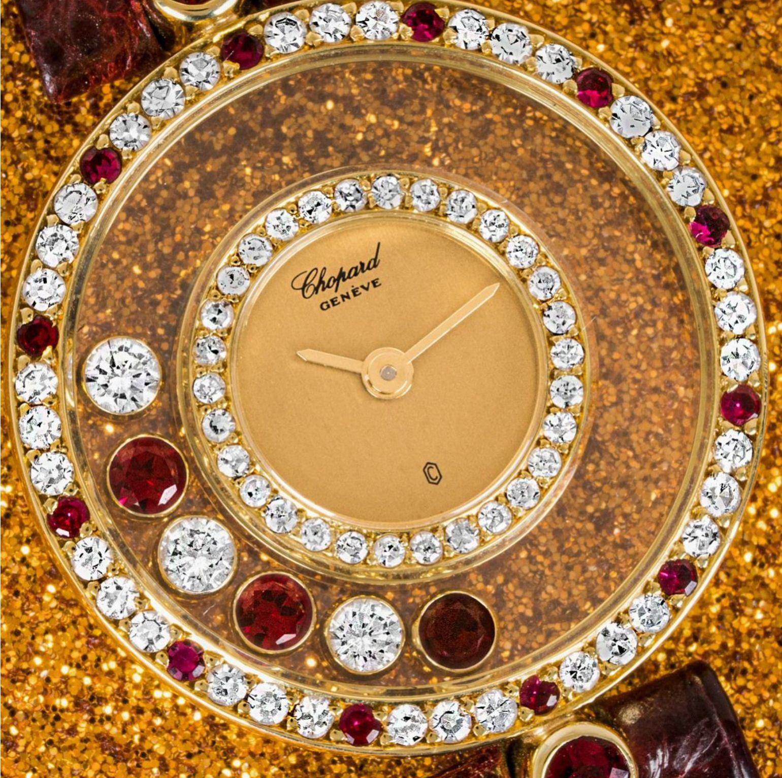 A stunning ladies yellow gold Happy Diamonds wristwatch by Chopard. Featuring a champagne dial with 6 floating rubies & diamonds, and a yellow gold bezel set with 66 round brilliant cut diamonds and 12 rubies. The watch also features 2 ruby-cut