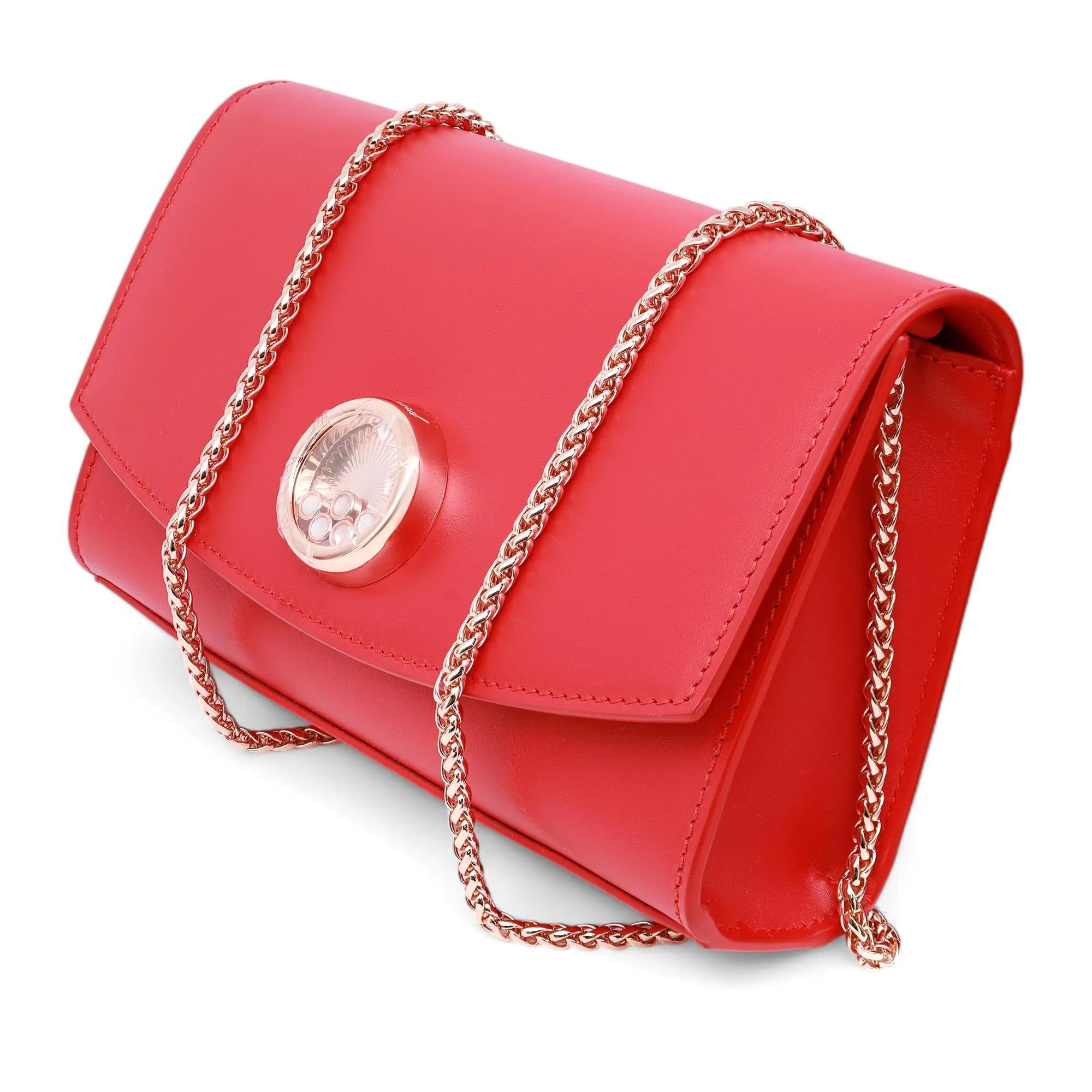 Chic y vibrante, este bolso rojo de piel de becerro permite libertad de movimientos gracias a su correa ajustable para el hombro. Adornada con el motivo circular magnético de color oro rosa con 5 nácares móviles engastados en bisel. Viene con