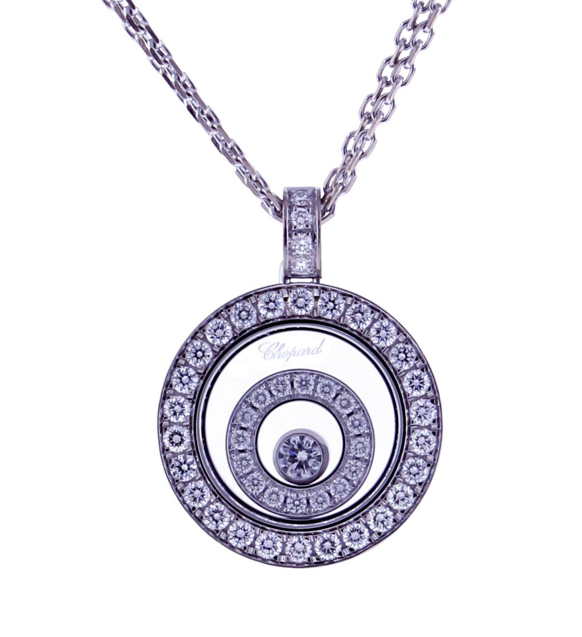 Chopard's Happy Spirit collection showcases this luminous circle pendant. Fashioned in 18 karat white gold, this pendant features two diamond circles that rest one inside the other while orbiting one floating diamond.  The 46 diamonds weigh .62