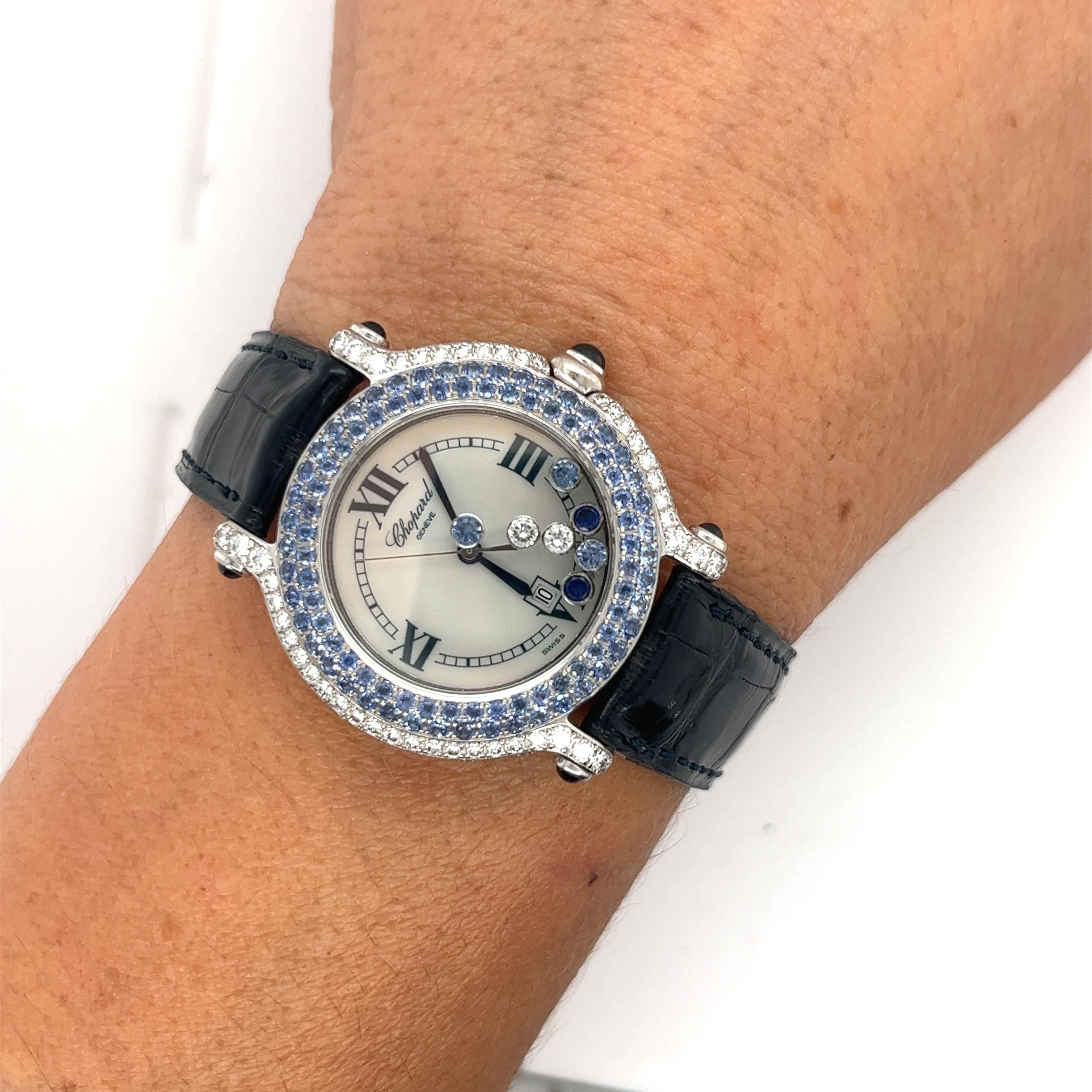 Chopard Happy Sport 18k white gold 33mm quartz ladies watch with crocodile skin leather strap. Set with round and cabochon cut Blue Sapphires and Diamonds around the bezel, case, and crown. Wide lugs set with cabochon cut Blue Sapphires. Featuring