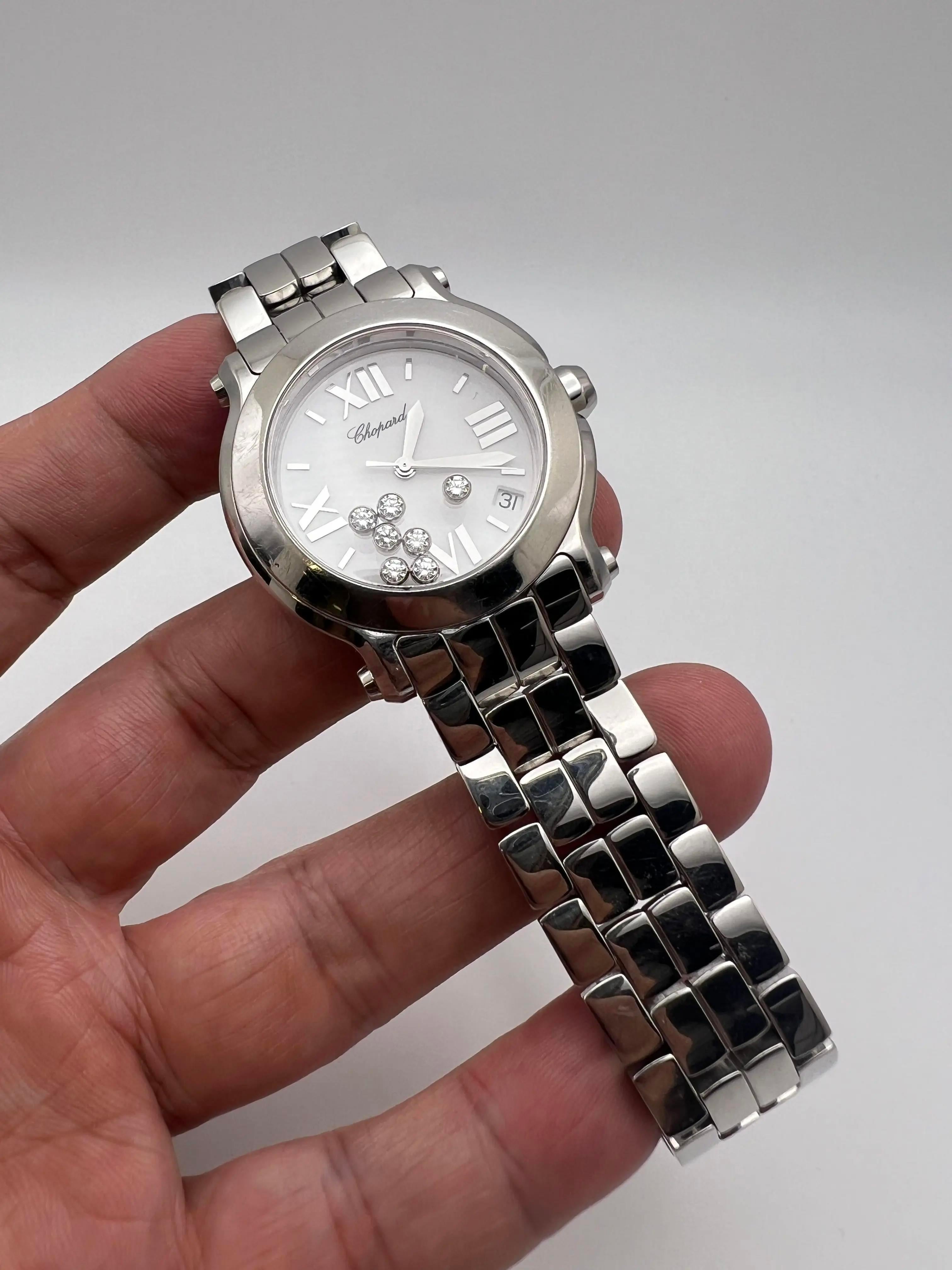 La montre Chopard Happy Sport pour femme (modèle 8475) est une pièce d'horlogerie étonnante dotée d'un boîtier et d'un bracelet en acier inoxydable poli. Le cadran de la montre est orné des diamants flottants caractéristiques de la collection Happy