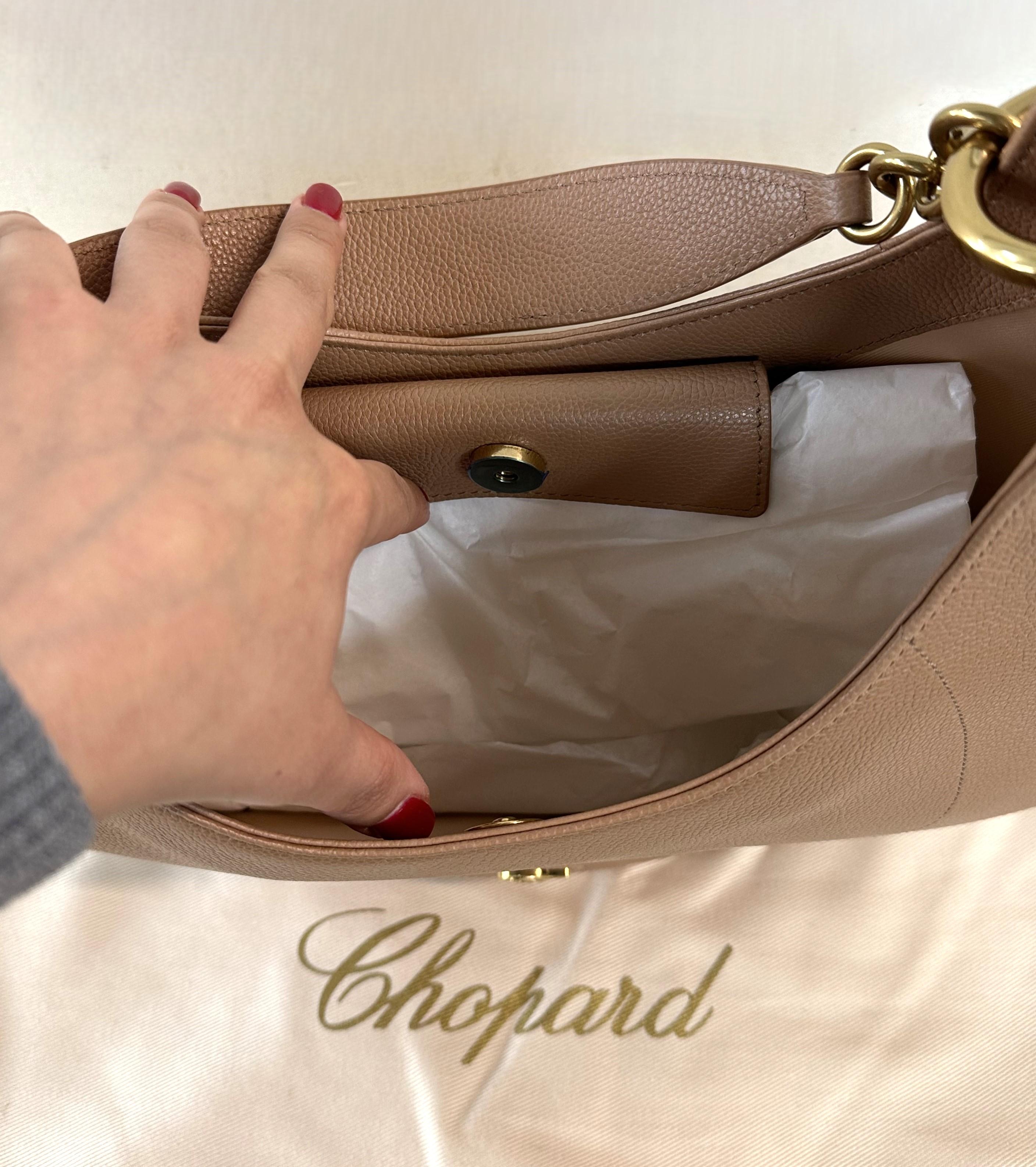 Este es un impresionante bolso hobo de la Colección Happy Sport de Chopard. Este bolso está fabricado en piel acolchada de color caramelo y luce la emblemática 