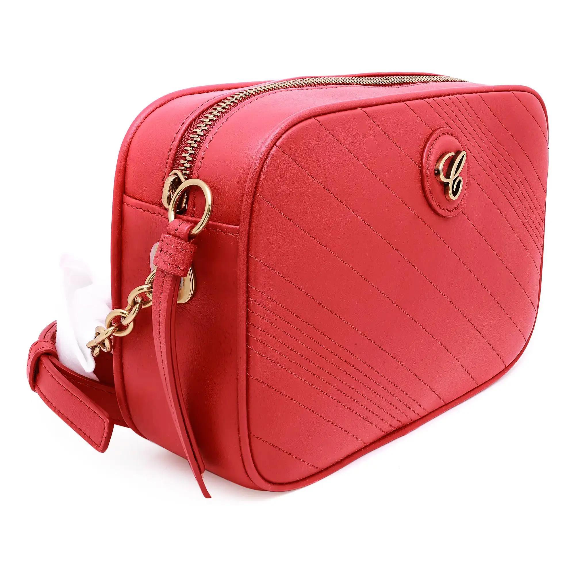 La Bolsa Crossbody para Cámara de Piel Roja Happy Sport de Chopard es un accesorio compacto y elegante que cuenta con un cierre de cremallera superior para un almacenamiento seguro. Fabricada en piel roja, luce un estampado de rayas diagonales