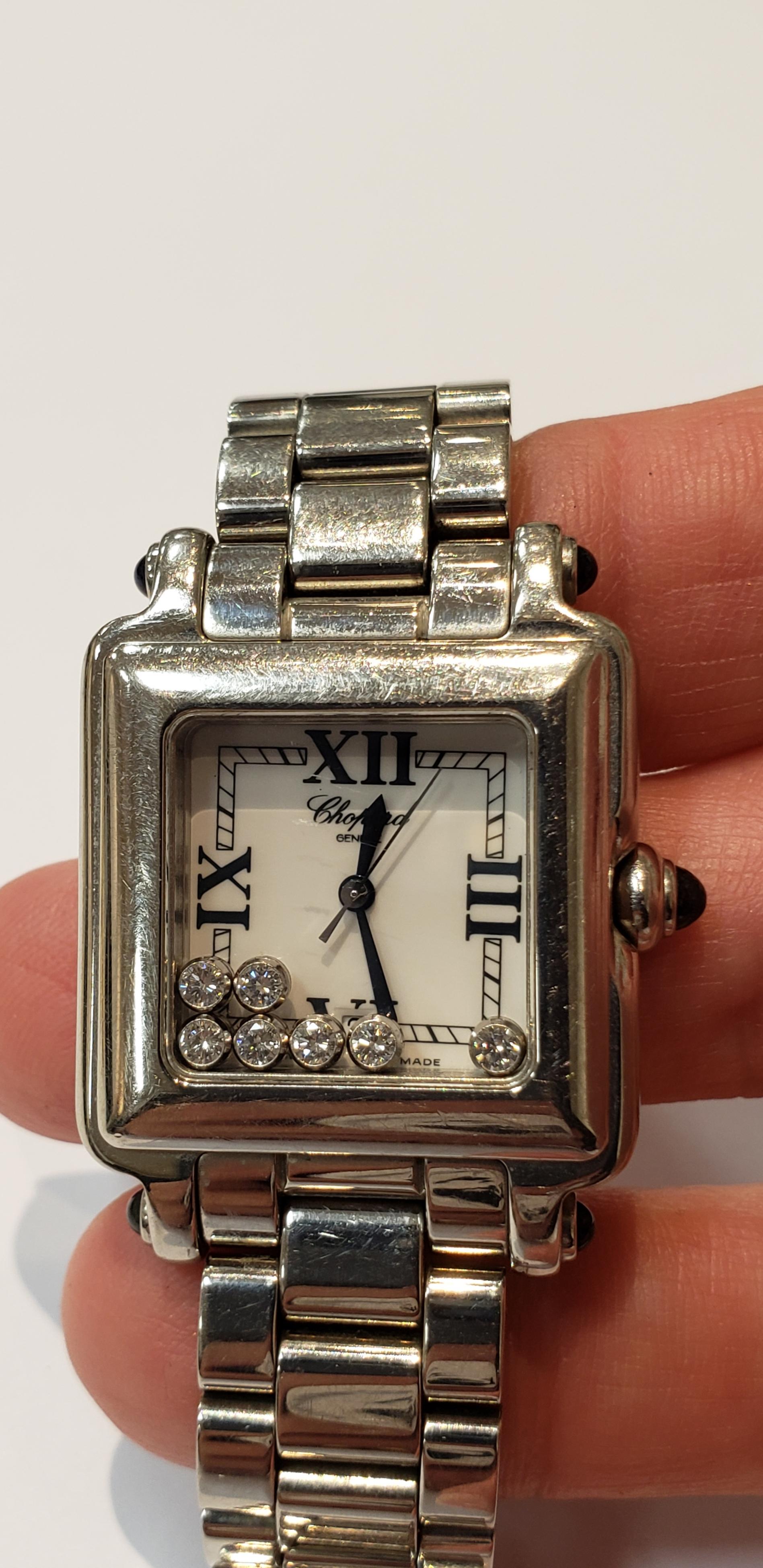 This is a pre-owned Chopard stainless steel Happy Sport watch with seven floating diamonds.
Watch has  a white dial with Roman numerals, a sweep second hand, & a quartz movement.
there are cabochon sapphires on the crown and lug ends. 7 diamonds