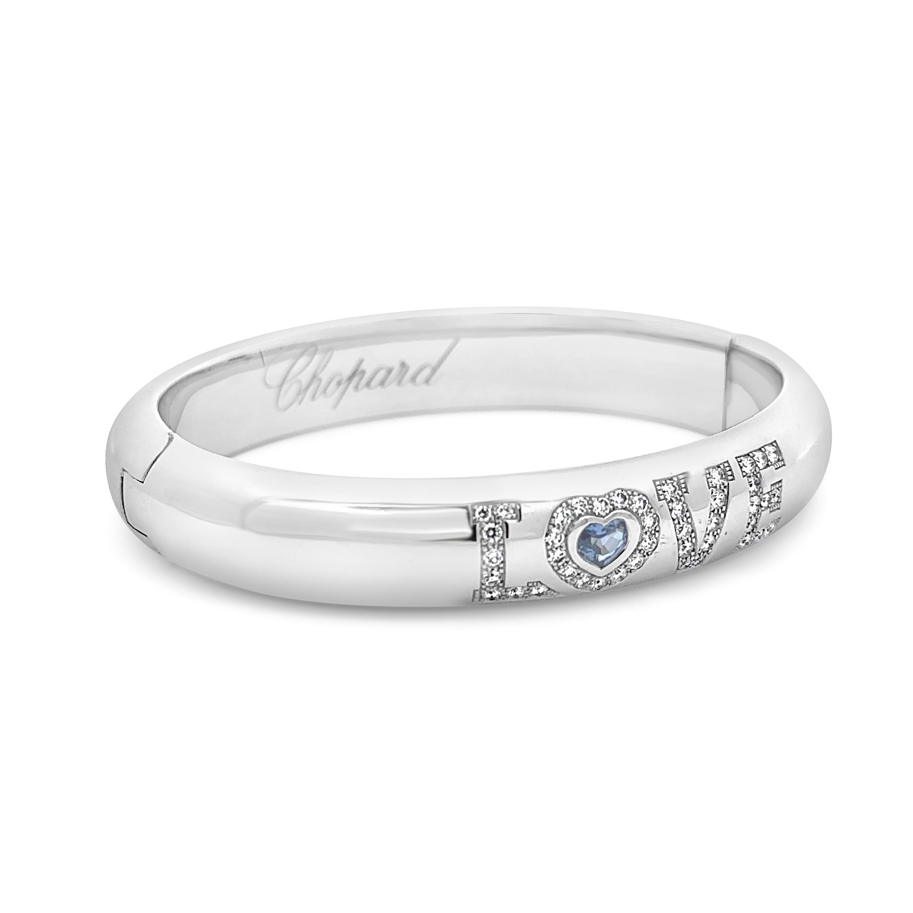 Ein modischer Armreif von Chopard mit einem blauen Saphir in Herzform von 0,83 Karat und 43 runden Diamanten im Brillantschliff von insgesamt 0,82 Karat, die entlang des Wortes LOVE gefasst sind. Fein gemacht mit 18K Weißgold, 7 Zoll im Umfang.