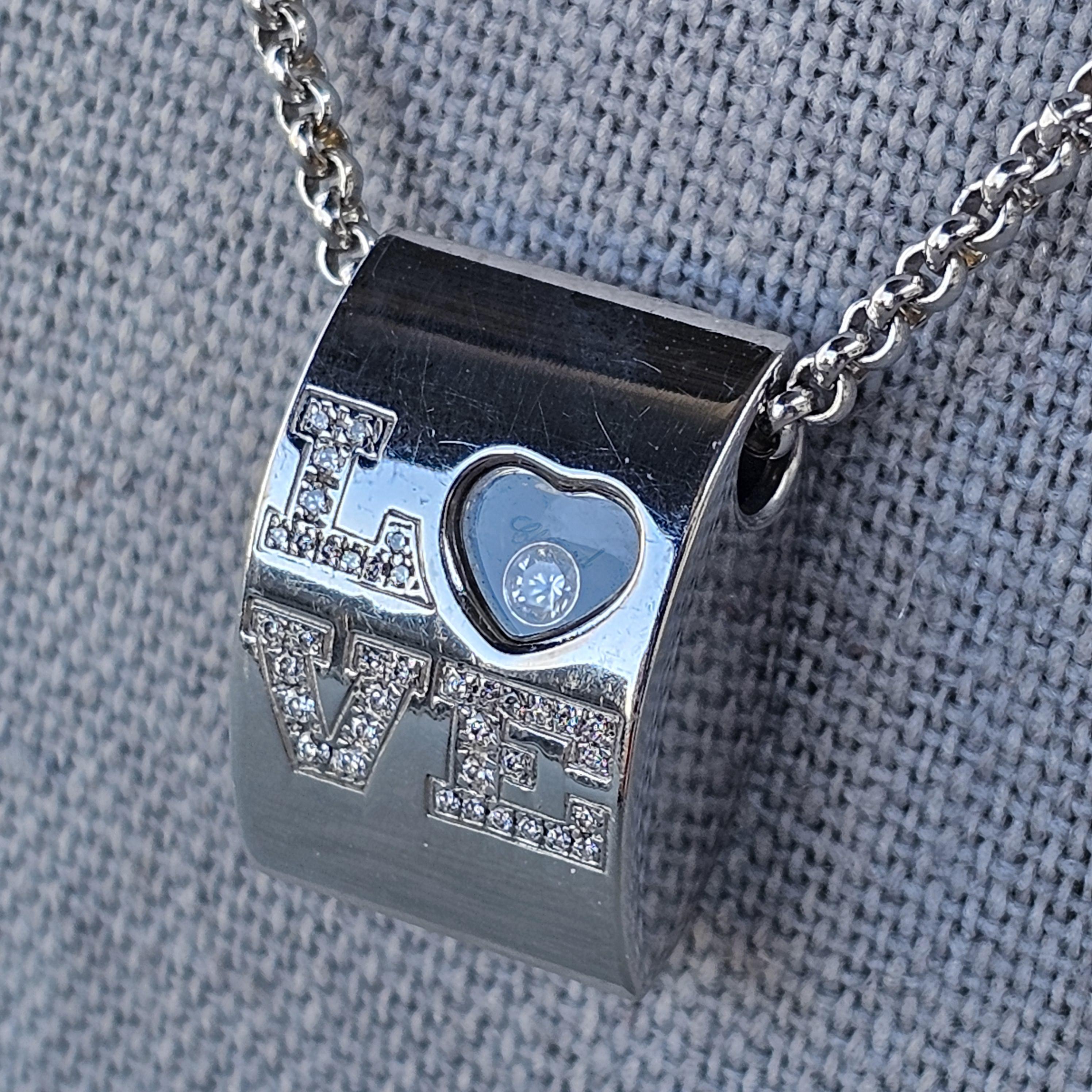 Ce collier pendentif en or blanc 18 carats de Chopard est un bijou raffiné. Il mesure 16,75 pouces de long et offre une tenue confortable. Le pendentif comporte le mot 