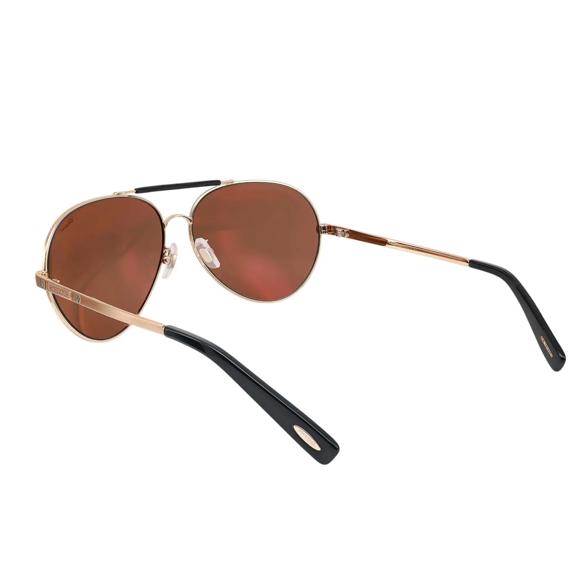 Voici les lunettes de soleil unisexes de luxe Chopard 95221-0239, parfaites pour la mode de rue. Ces lunettes de soleil présentent une monture en métal or rose avec des branches noires et des verres polarisés gris/vert. Les bras sont élégamment