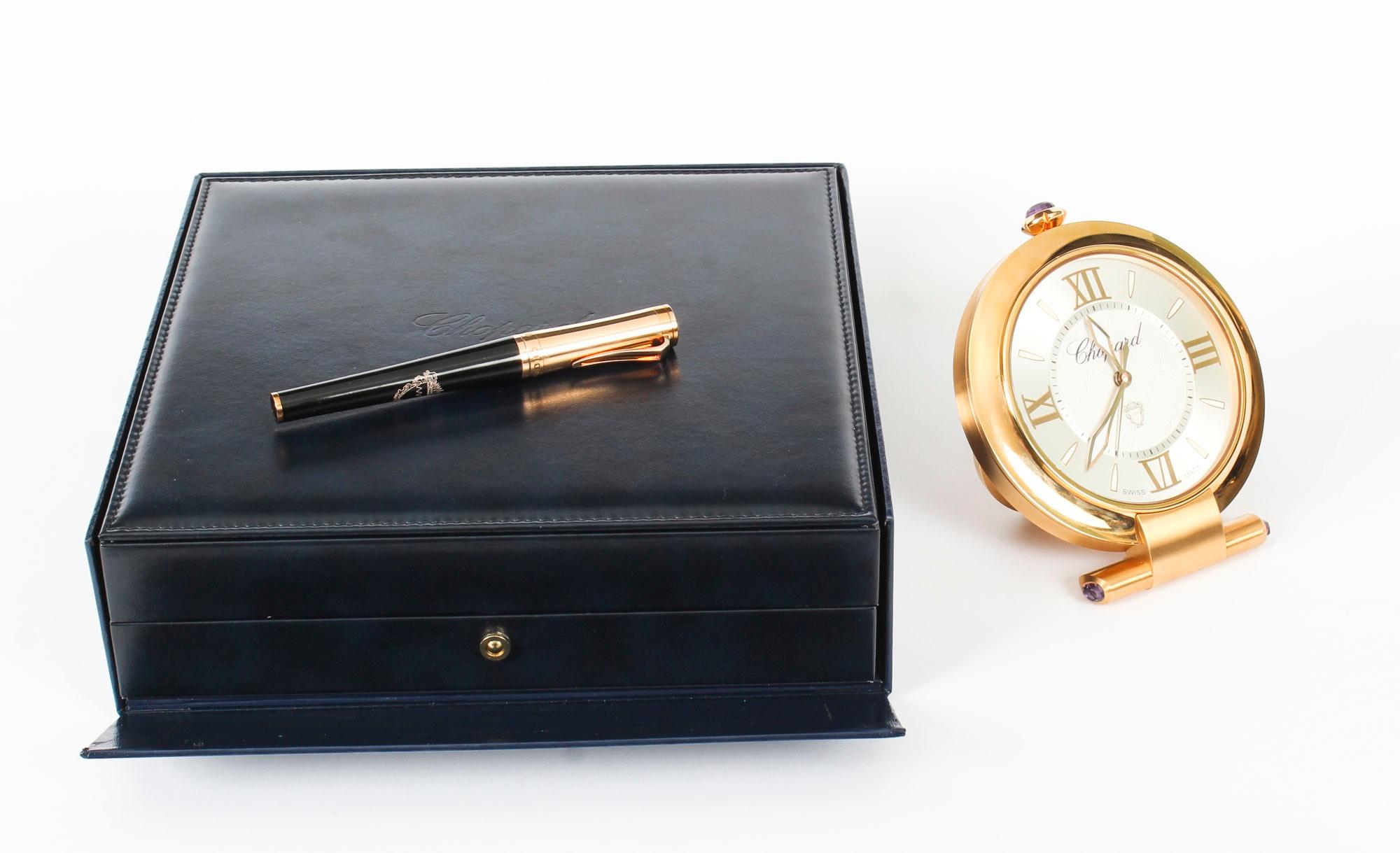 A majestic presentation compendium comprising a Chopard Imperiale travelling alarm clock and a Chopard pen, late 20th Century in date.

The clock is made of 18kt rose gold plated steel with silvered dial and Roman numerals alongside