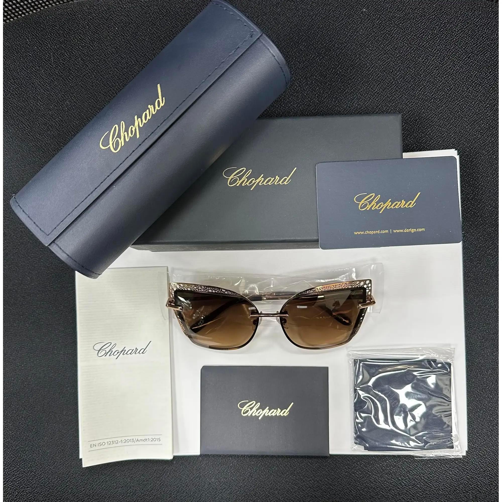 Introducing the luxury unisex Chopard Sunglasses 95221-0419, perfect for street fashion. These sunglasses showcase a shiny copper gold brown gradient lenses in rimless metal frame. The arms are elegantly adorned with the Chopard logo. The dimensions