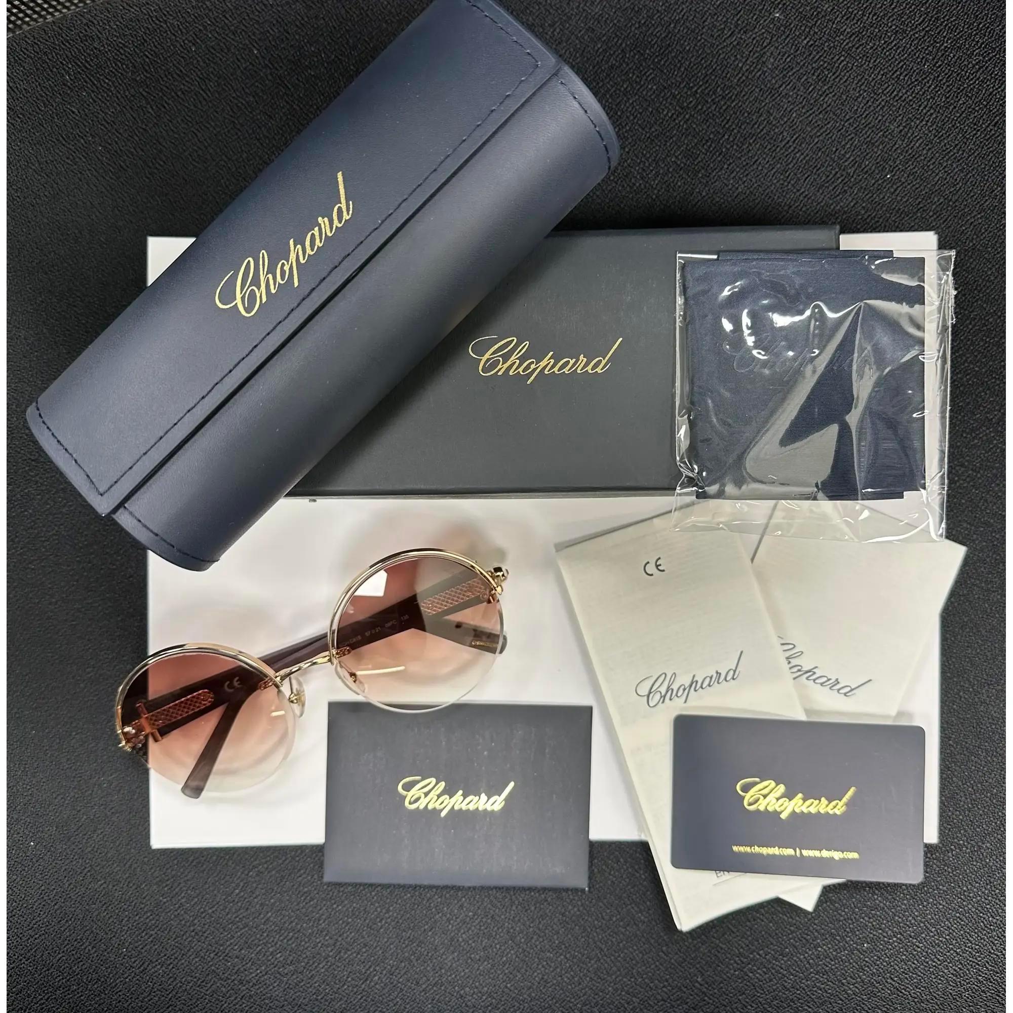 Presenting the luxury unisex Chopard Sunglasses 95221-0472, ideal for street fashion. These sunglasses feature a shiny copper gold metal/acetate frame with leather and strass and brown with gradient lenses. The arms are adorned with the Chopard