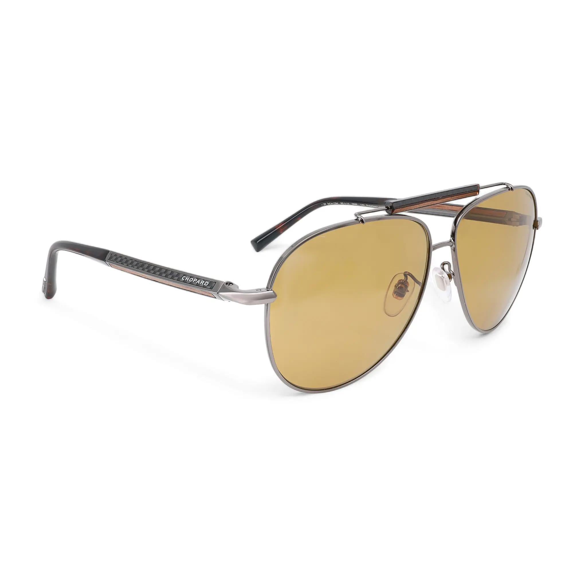 Presenting the luxury unisex Chopard Sunglasses 95221-0527, ideal for street fashion. These sunglasses feature a shiny light gold metal frame with orange with logomania mirrored gold lenses. The arms are adorned with the Chopard logo. The dimensions