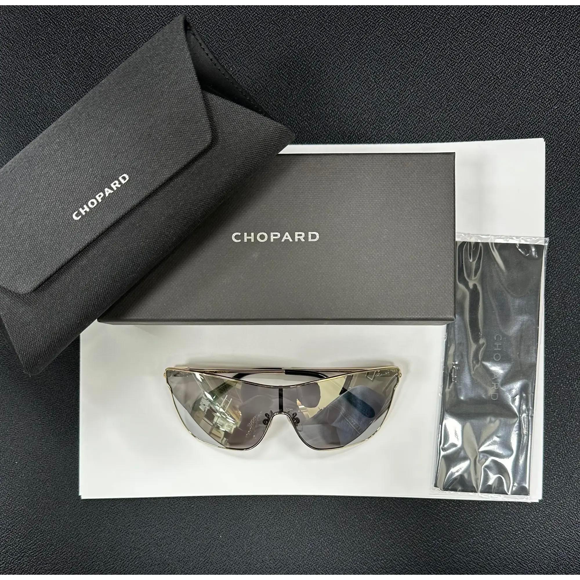 Presenting the luxury unisex Chopard Sunglasses 95221-0404, ideal for street fashion. These sunglasses feature a shiny light gold metal frame with smoke ivory mirrored lenses. The arms are adorned with the Chopard logo. The dimensions are as