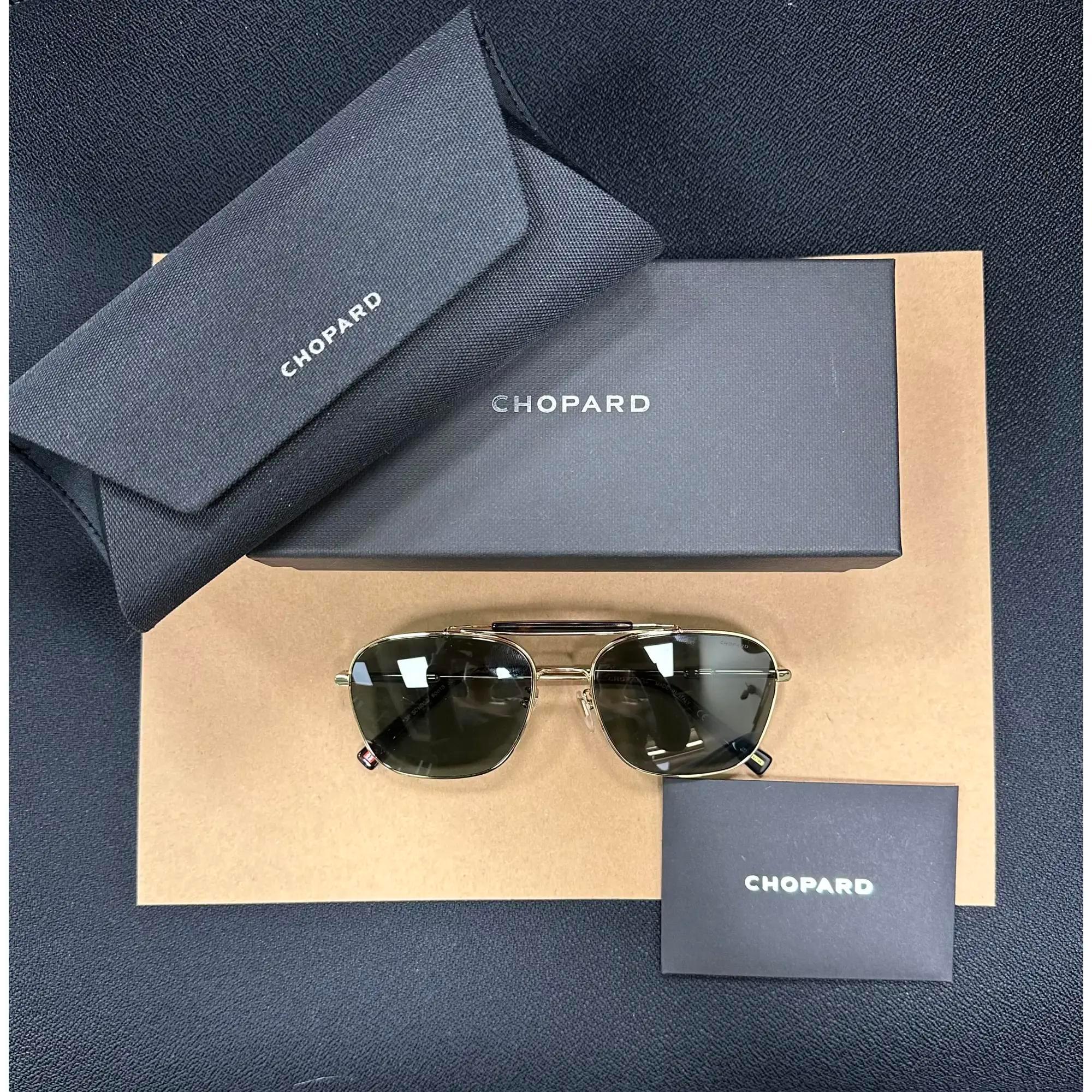Presenting the luxury unisex Chopard Sunglasses 95221-0544, ideal for street fashion. These sunglasses feature a shiny rose gold metal frame with gray/green color polarized lenses. The arms are adorned with the Chopard logo. The dimensions are as