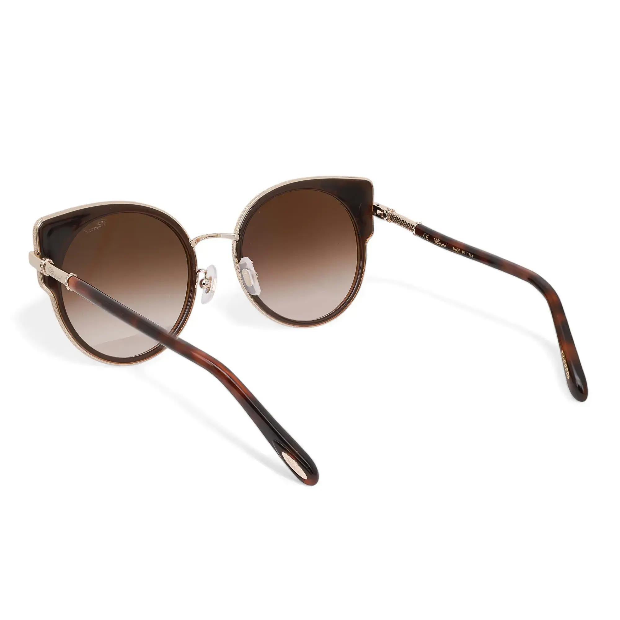 Presenting the luxury unisex Chopard Sunglasses 95221-0443, ideal for street fashion. These sunglasses feature a shiny rose gold metal/injected frame with strass and brown gradient lenses. The arms are adorned with the Chopard logo. The dimensions