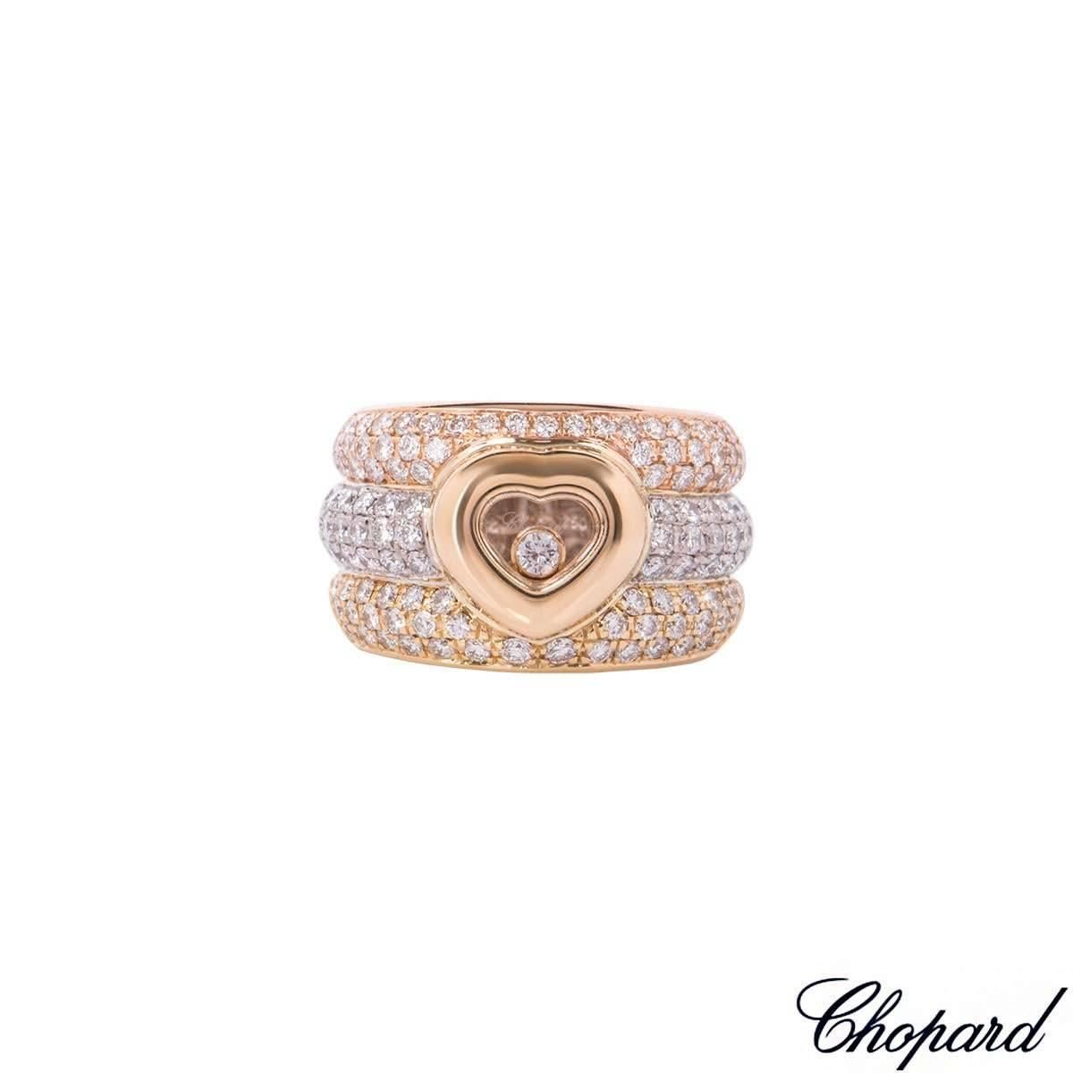 An 18k tri-colour gold Happy Diamonds ring by Chopard. The ring is composed of 3 bombé pave set segments with a small heart motif in the centre. The heart motif has a pane of glass enclosing a small round brilliant cut floating diamond. The floating