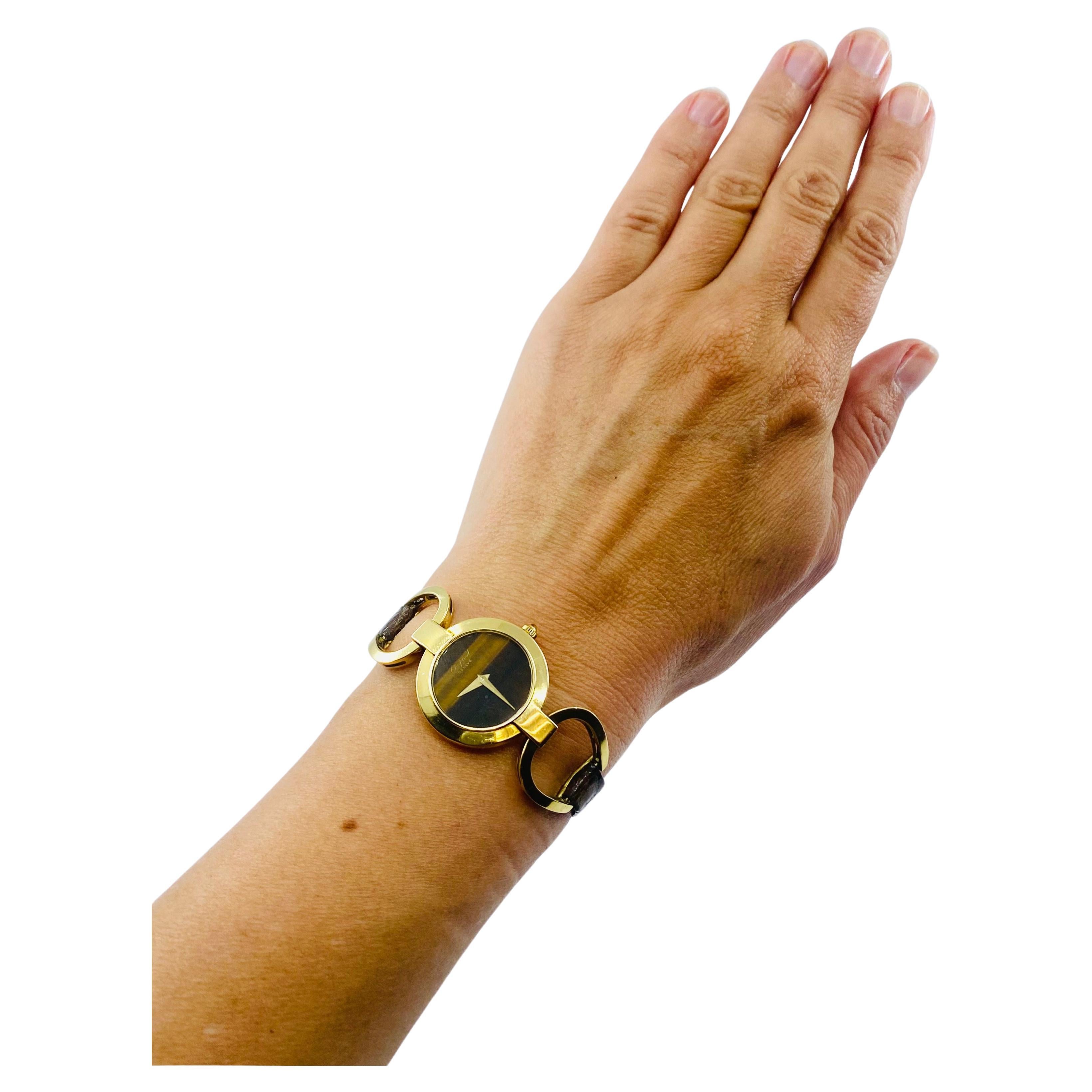 Une rare montre Chopard en or 18 carats, ornée d'un œil de tigre.
Le boîtier est rond, avec un fond de boîtier encliquetable et des cornes fixées à l'équitation en or.
éléments. Le cadran sans chiffres est fait d'oeil de tigre avec une grande