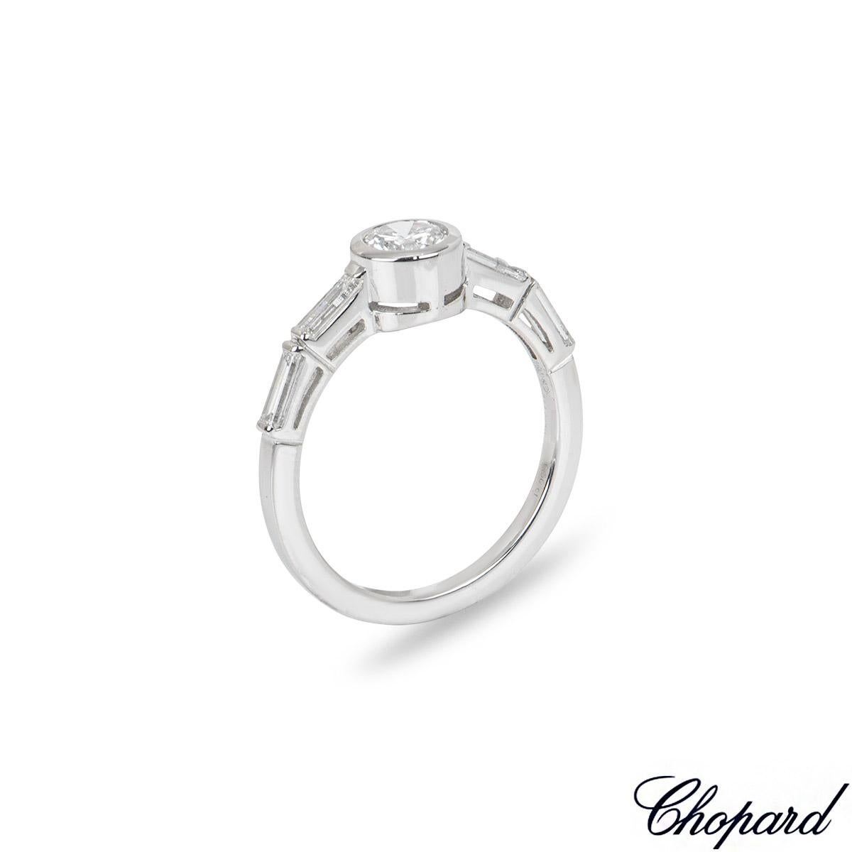 A classy 18k white gold diamond ring by Chopard. The ring is set to the centre with a round brilliant cut diamond in a modern bezel setting weighing 0.50ct, E-F colour and VS clarity. Complementing the centre stone are 4 baguette cut diamonds set to