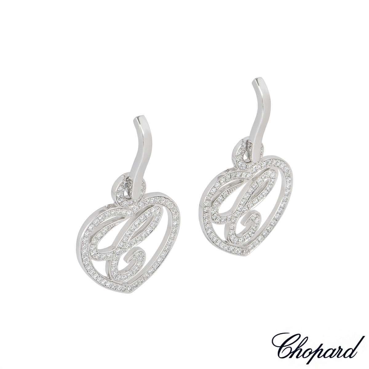A paid of 18k white gold earrings from the Happy Diamonds collection by Chopard. The earrings feature a diamond set openwork heart with a C in the centre. The earrings have a total of 188 round brilliant cut diamonds totalling 0.46ct, F-G colour and