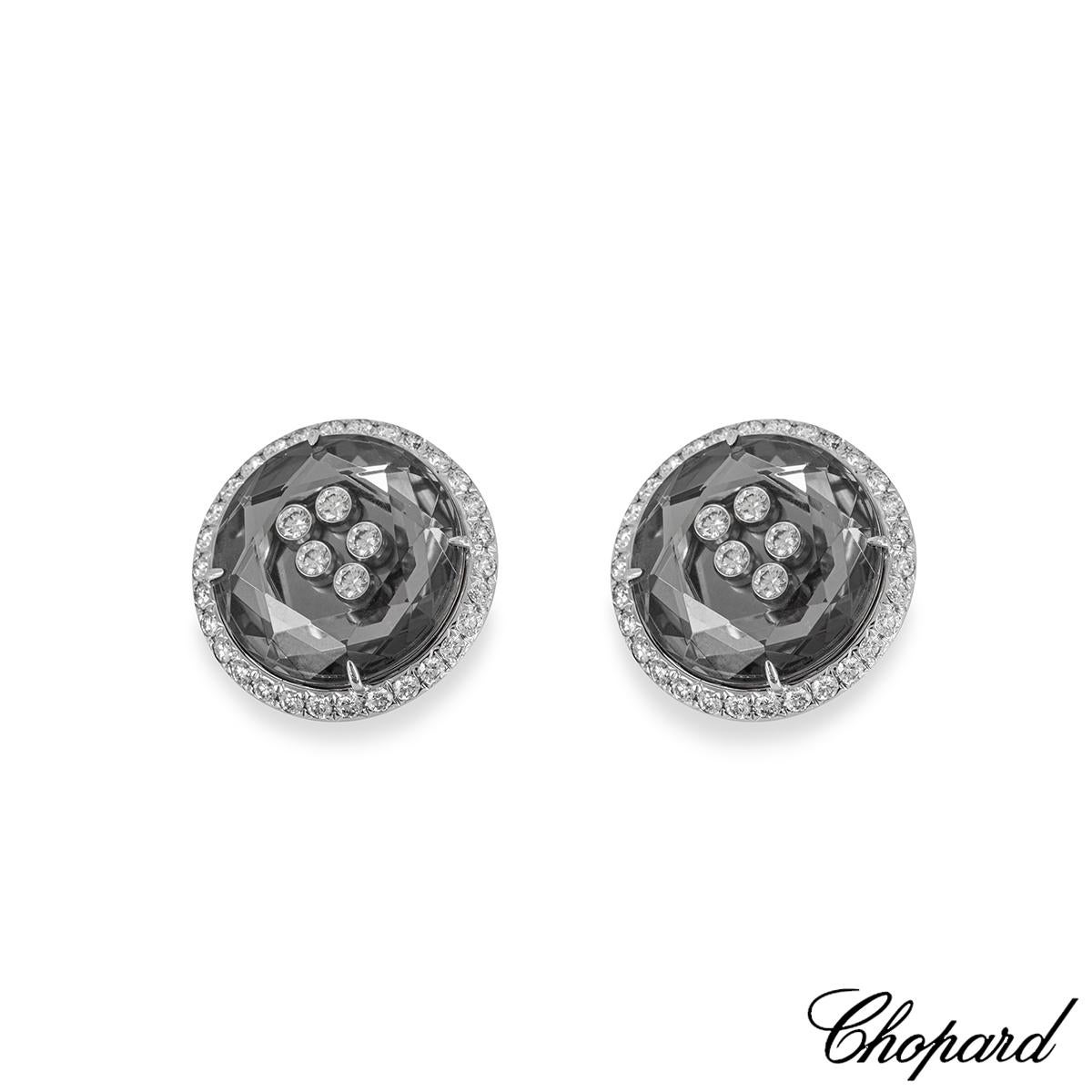 A lively pair of 18k white gold earrings by Chopard from the Happy Diamonds collection. The round ear clips are each set with 5 round brilliant cut diamonds floating behind a faceted glass with a total weight of 0.30ct. Set to the outer edge of each