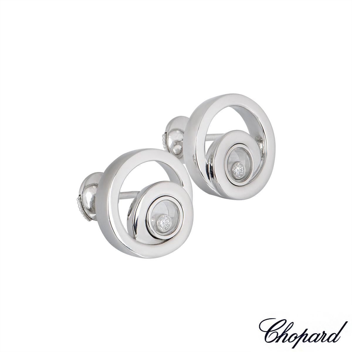 A pair of 18k white gold earrings by Chopard from the Happy Diamonds collection. The earrings are composed of two entwined circular motifs featuring the iconic floating diamond enclosed between two pieces of Chopard signed glass totalling 0.11ct.