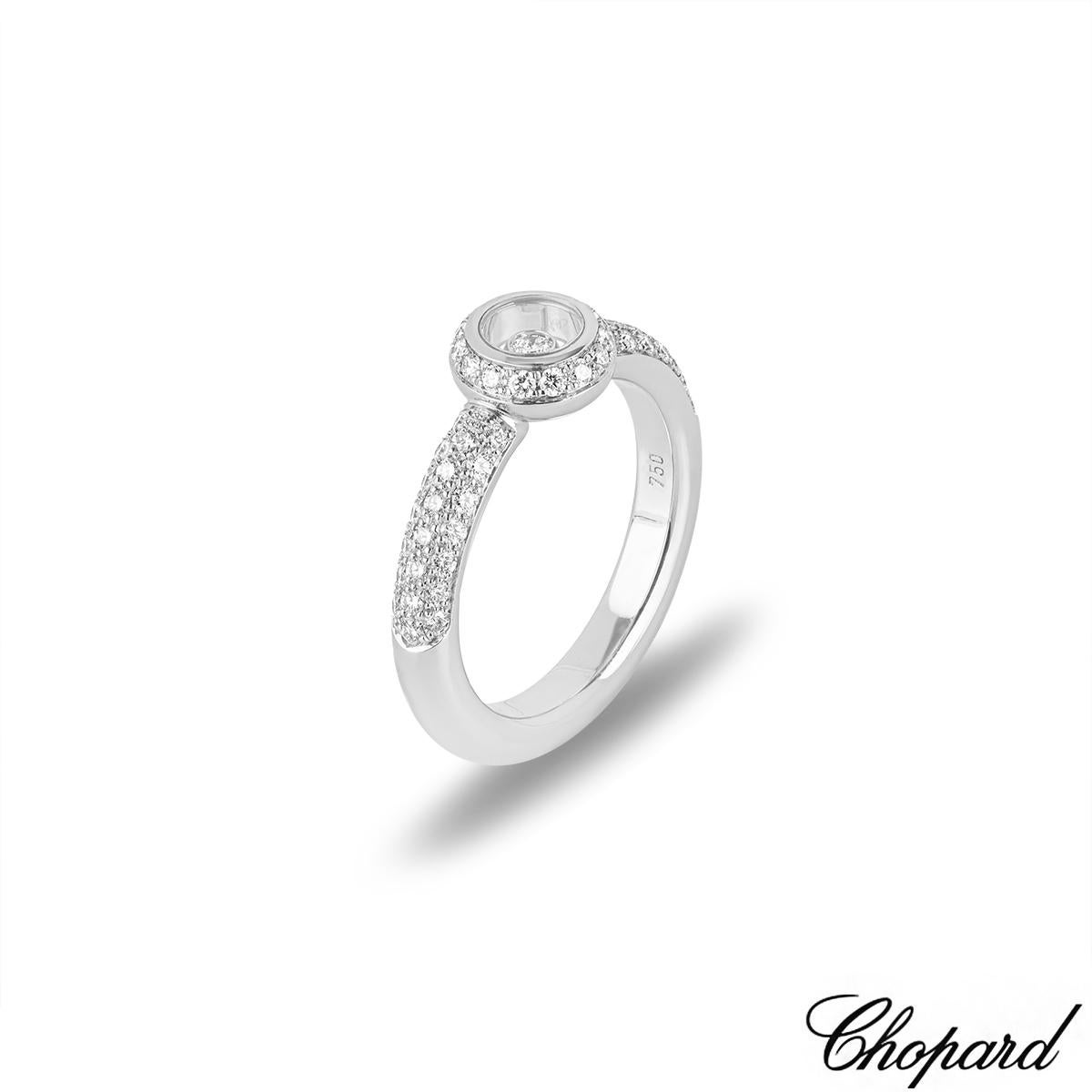 A sparkly 18k white gold Happy Diamonds ring by Chopard. The ring features a circular motif set to the centre with a halo of 15 round brilliant cut diamonds with an approximate weight of 0.13ct. In the centre of the circular motif is a single round