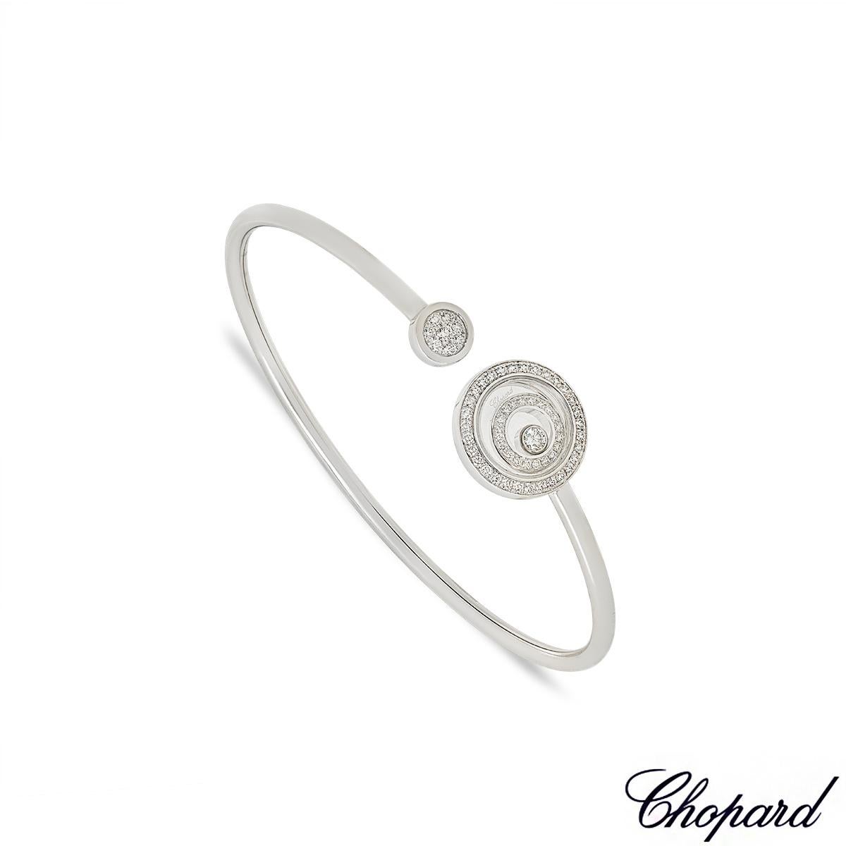 A beautiful Chopard 18k white gold diamond cuff bangle from the Happy Spirit collection. The cuff style bangle has a circular shaped talisman on either end, one with a floating round brilliant cut diamond inside a floating surround encased behind