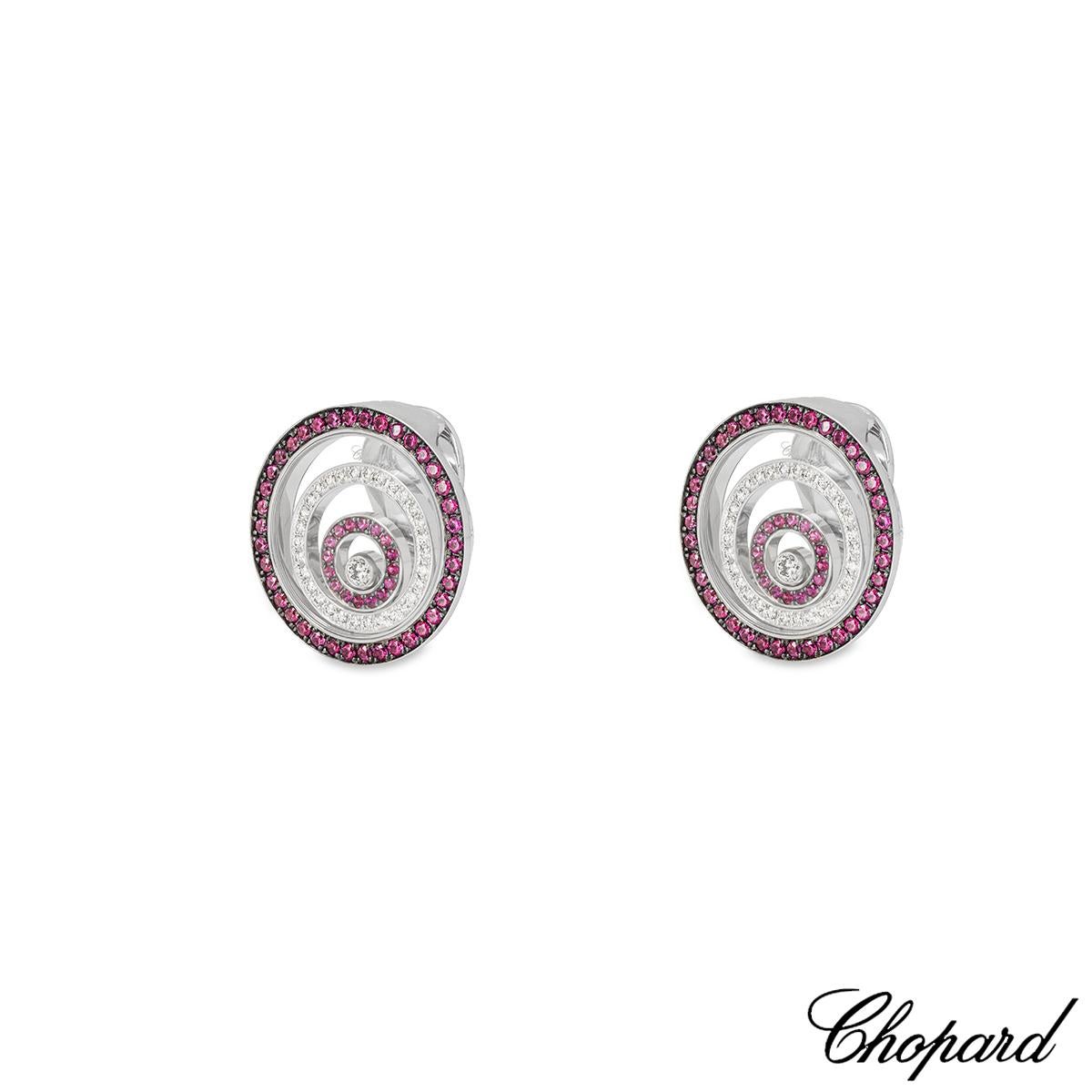An enchanting pair of 18k white gold ruby and diamond earrings by Chopard from the Happy Spirit collection. The earrings feature three graduating circular motifs set inside each other. The outer and inner circles are pave set with 54 round cut