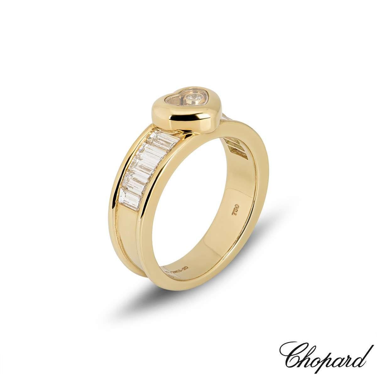 An 18k yellow gold ring from the Chopard Happy Diamond collection. The ring is set to the centre with a heart motif, made up of the iconic Chopard signed glass, encasing a 0.05ct single floating diamond. Complementing the motif are trapezium cut