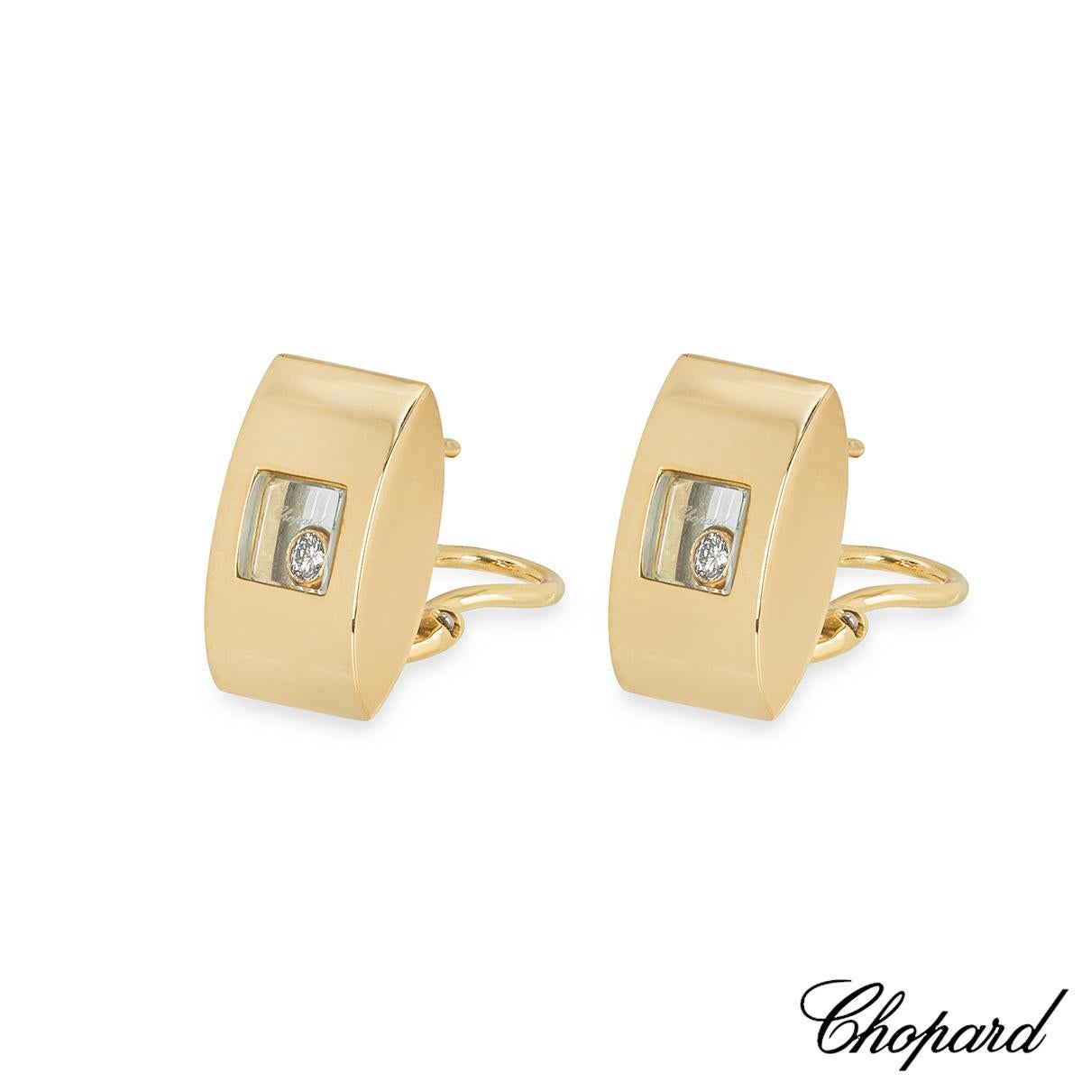 A pair of 18k yellow gold earrings by Chopard from the Happy Diamonds collection. The earrings feature a curved rectangular design with a single floating diamond encased behind the iconic Chopard signed glass. The diamonds have a total weight of