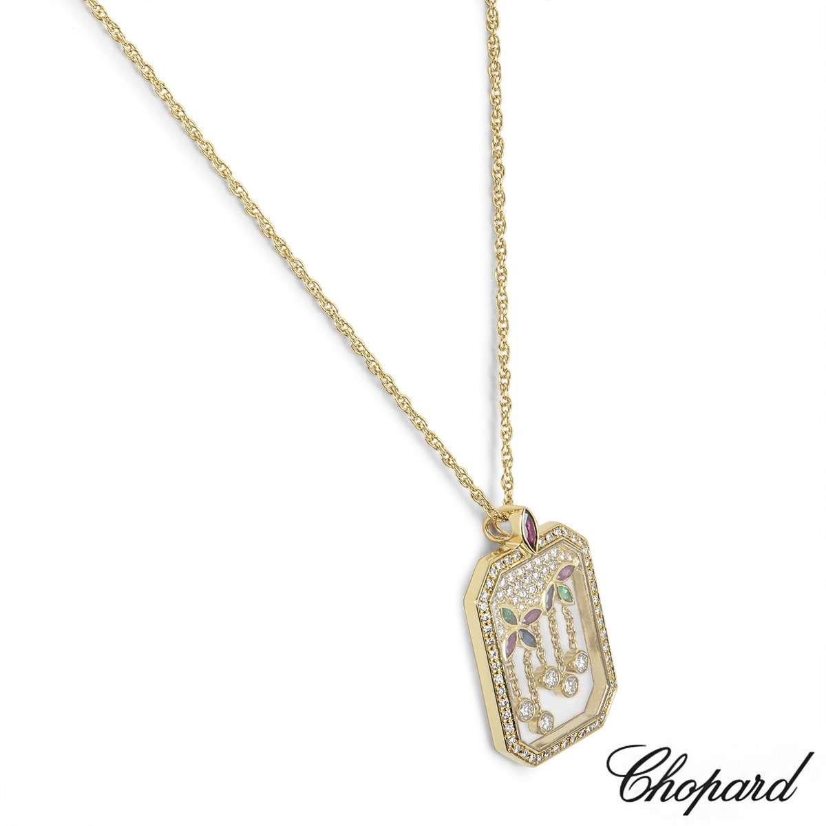 An elegant 18k yellow gold pendant by Chopard. The pendant features a rectangular glass motif encasing a floral design floating in the centre. The motif is set with diamonds, sapphires, rubies and emeralds. The pendant comes on an 18 inch chain