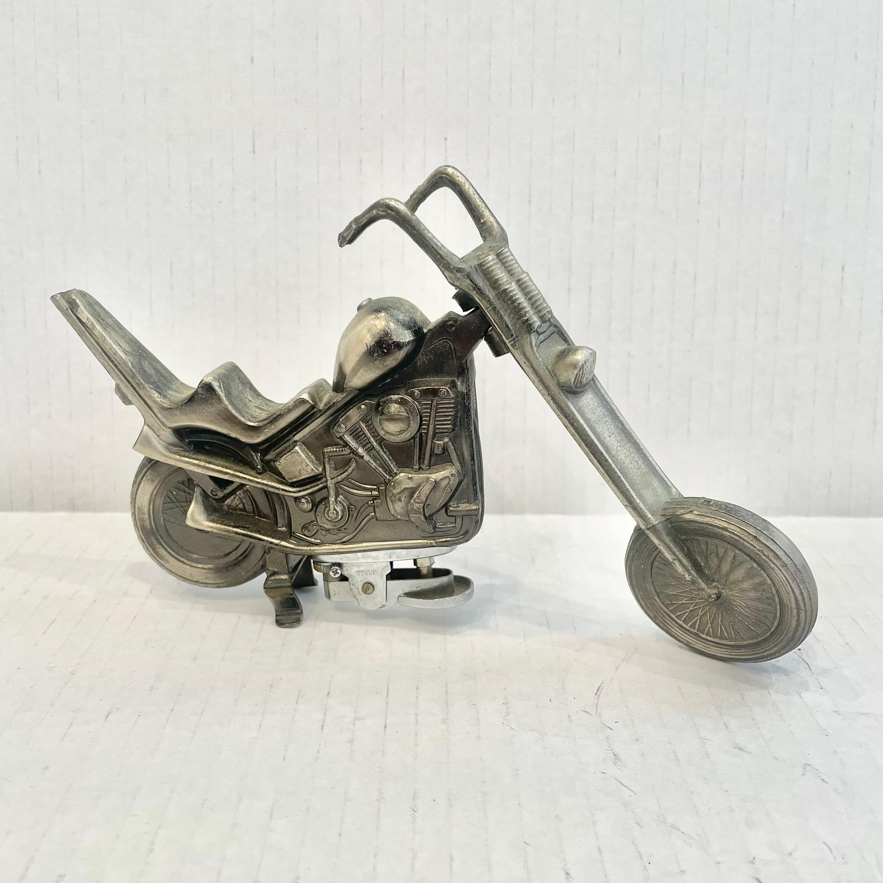Cool vintage table lighter in the shape of a two seat chopper motorcycle. Made completely of metal with a hollow body. Beautiful burnished silver color with intricate details. Tip of backrest is broken off. Cool tobacco accessory and conversation