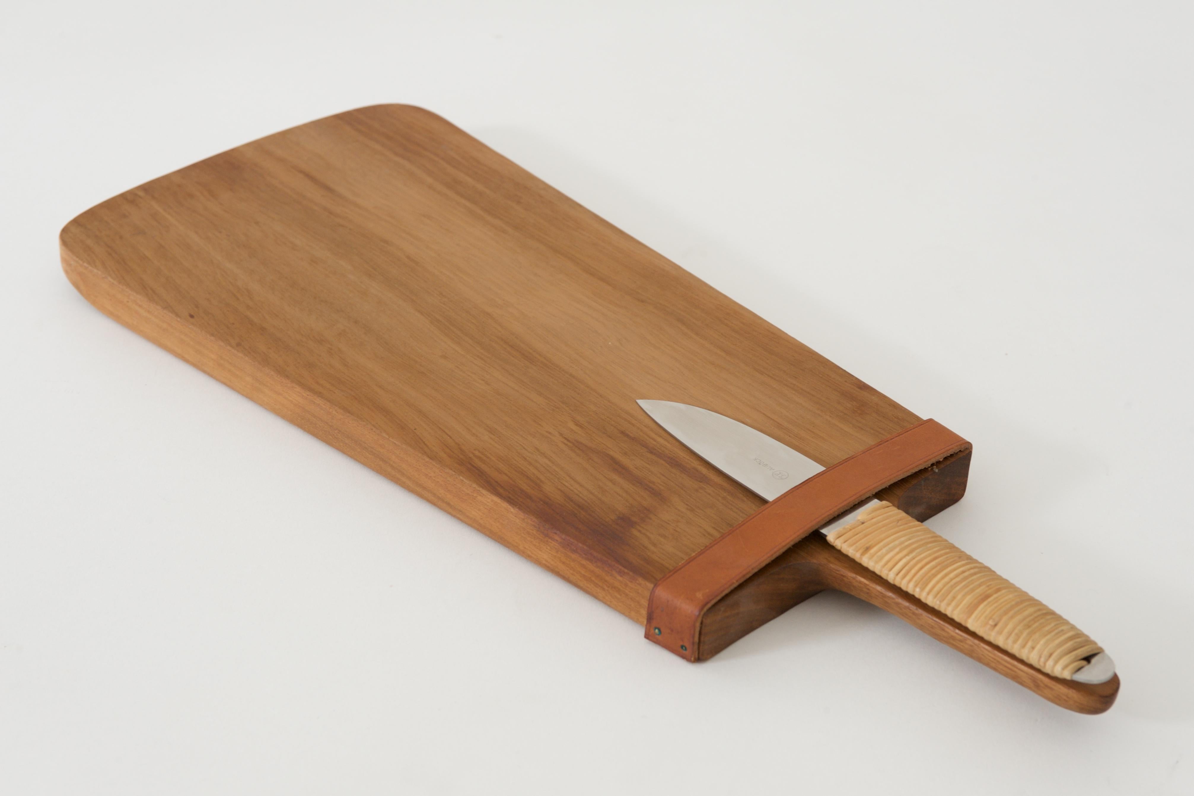 Chopping board with a Knife
Designed by Carl Auböck, 1950s

Nutwood, leather, stainless steel, raffia
Knife marked with AUBÖCK, Amboss Logo, Stainless, Austria

Measure: D 19.6, W 48 cm, H 2.2 cm / D 7.71 in, 18.89 in, 0.87 in
Knife: L 22.00