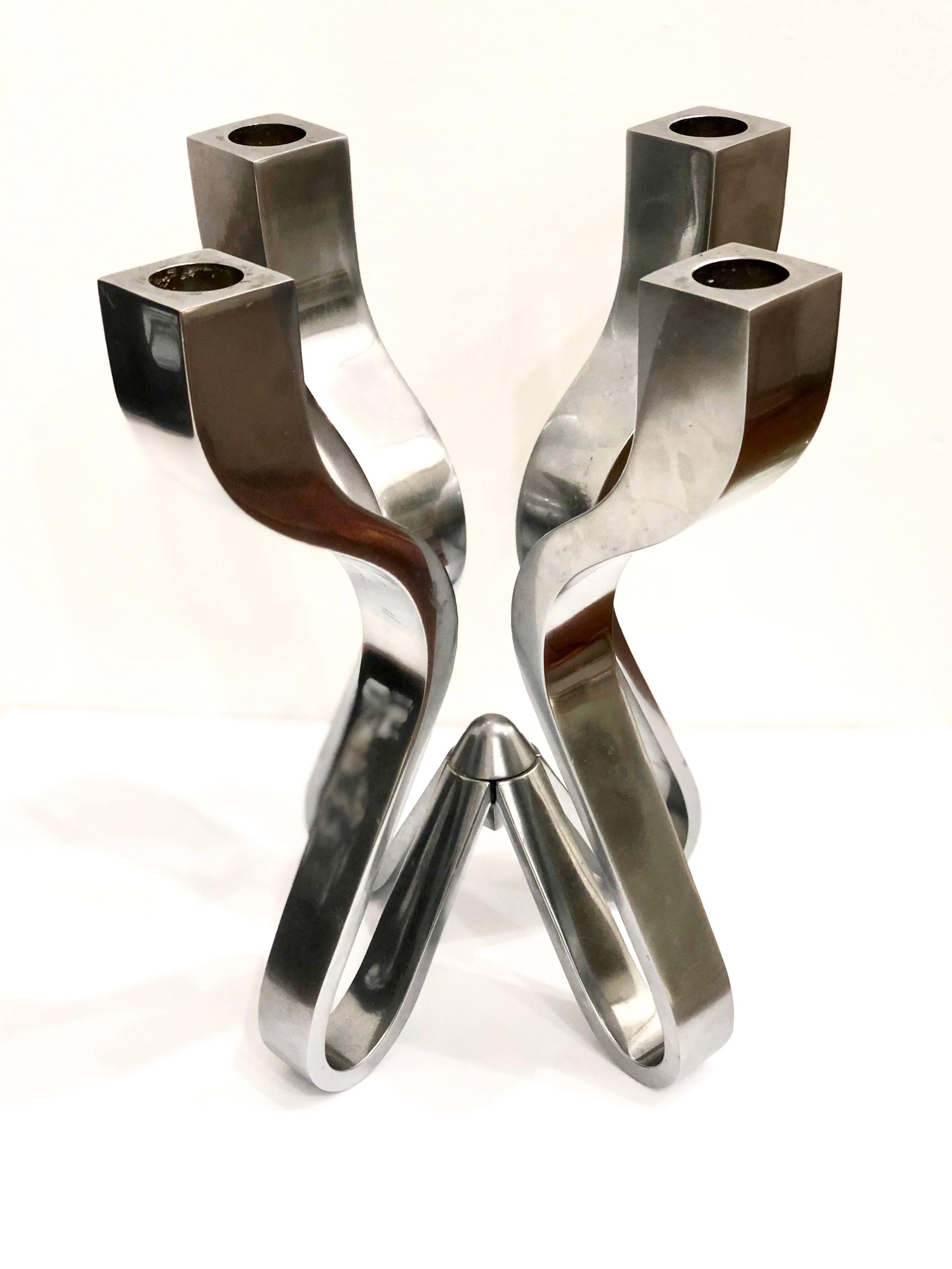 Striking candelabra. Described by their designer, Karim Rashid, as “sensual minimalism”, solid sleek awe-inspiring pieces of decorative art. Comprised of die-cast zinc with a matte chrome plating. Rashid has been deemed one of the most prolific