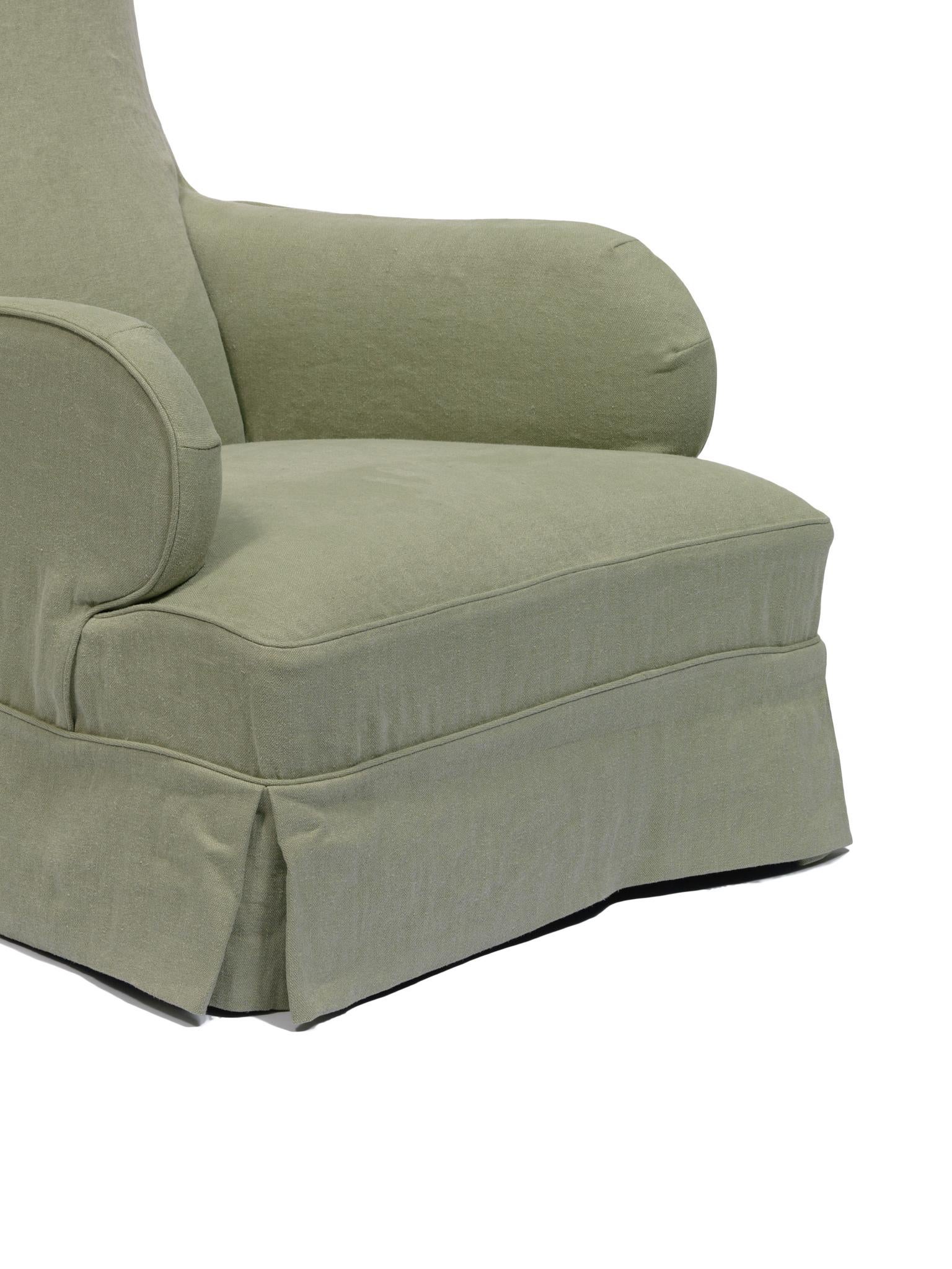 Le fauteuil club Chrissy de am designs est une interprétation contemporaine du fauteuil club classique. Fabriqué à la main en Belgique avec un cadre en bois massif, il présente une assise profonde, de larges accoudoirs et une silhouette basse et