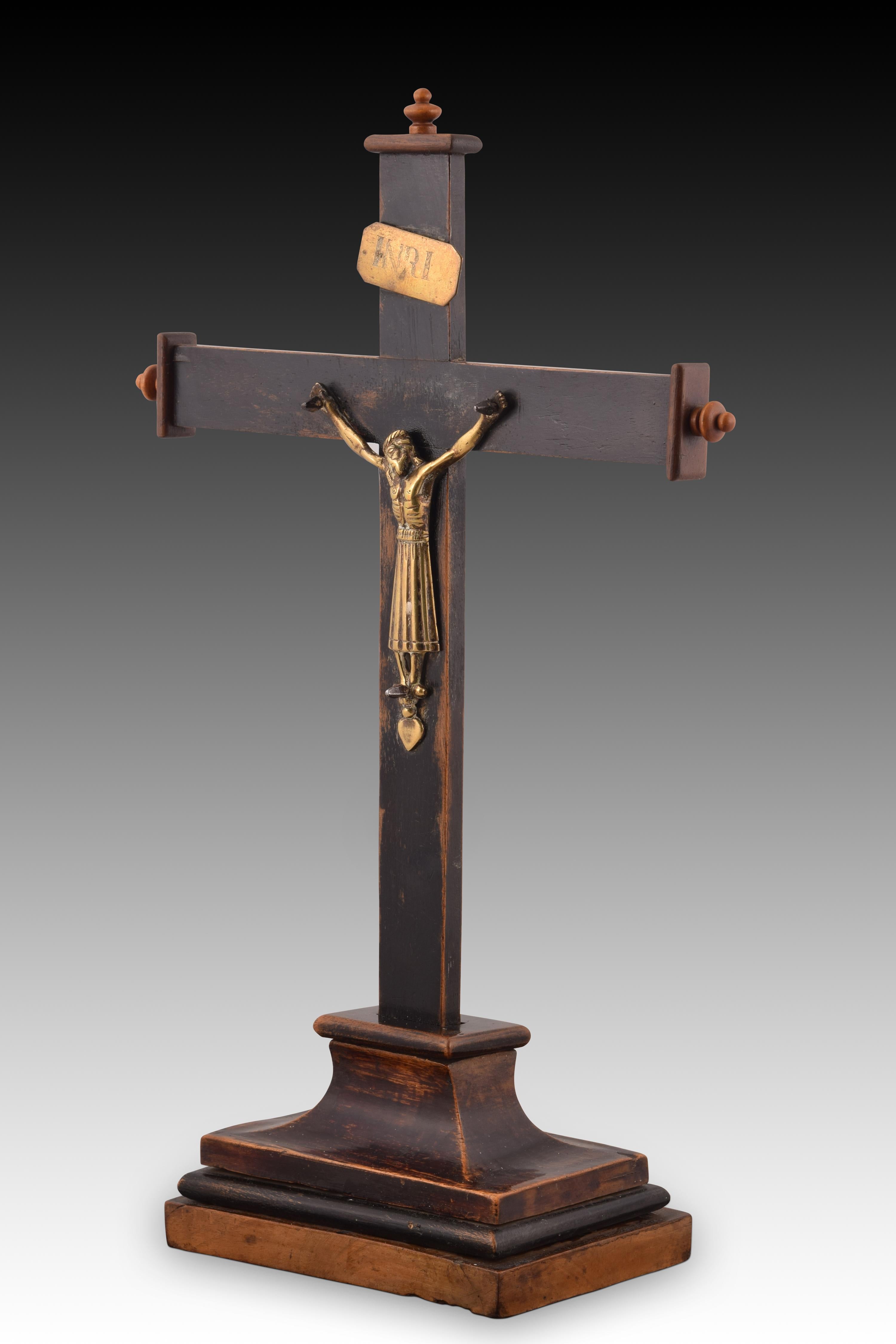 Christ of Burgos. Wood, metal. Spanish school, 19th century.
 A rectangular base serves as the base for a Latin cross with finials at the three upper ends. This has the usual “INRI” label and a particular figure of the Crucified Christ, with a very