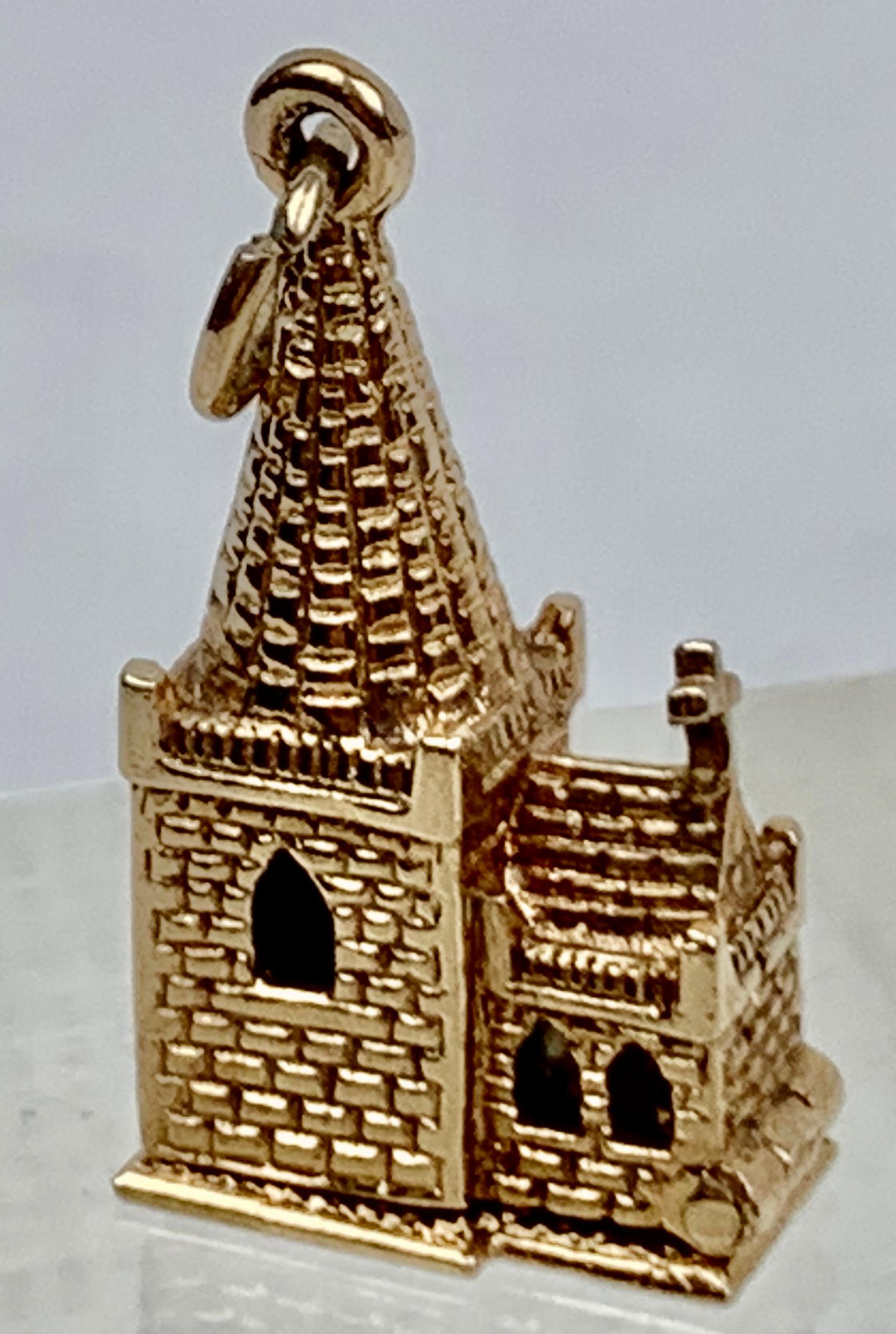 A solid gold charm of a church that opens to reveal a christening with a priest holding the infant while the parents look on.  The figures are colored with high fired enamel.
Hallmarked .375 (9 carat solid gold), Birmingham, England, 1976 on the