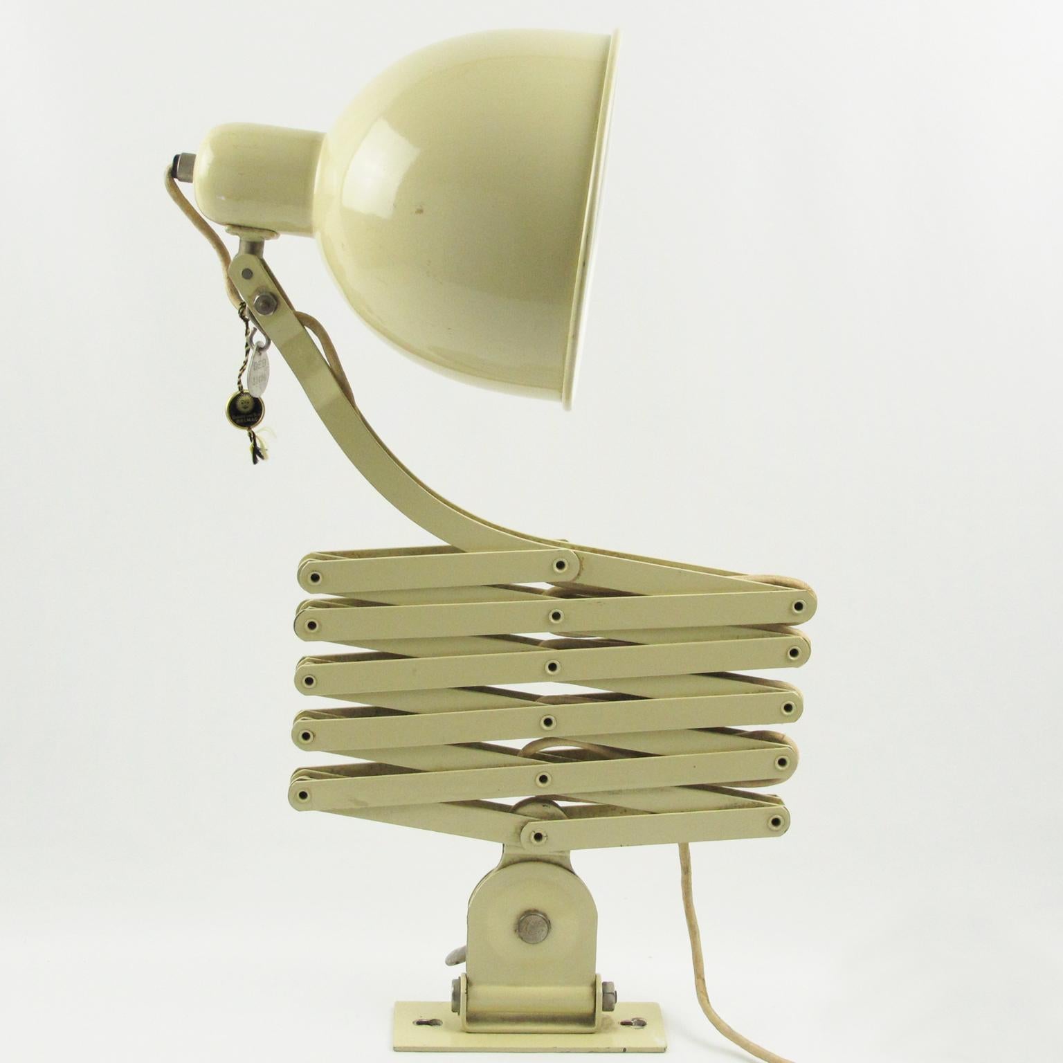 Il s'agit d'une lampe murale originale en métal extensible ou d'une applique à ciseaux conçue par le célèbre chef d'atelier de l'école du Bauhaus, Christian Dell, en 1933 pour Kaiser Idell. Cette version grand format présente une peinture métal