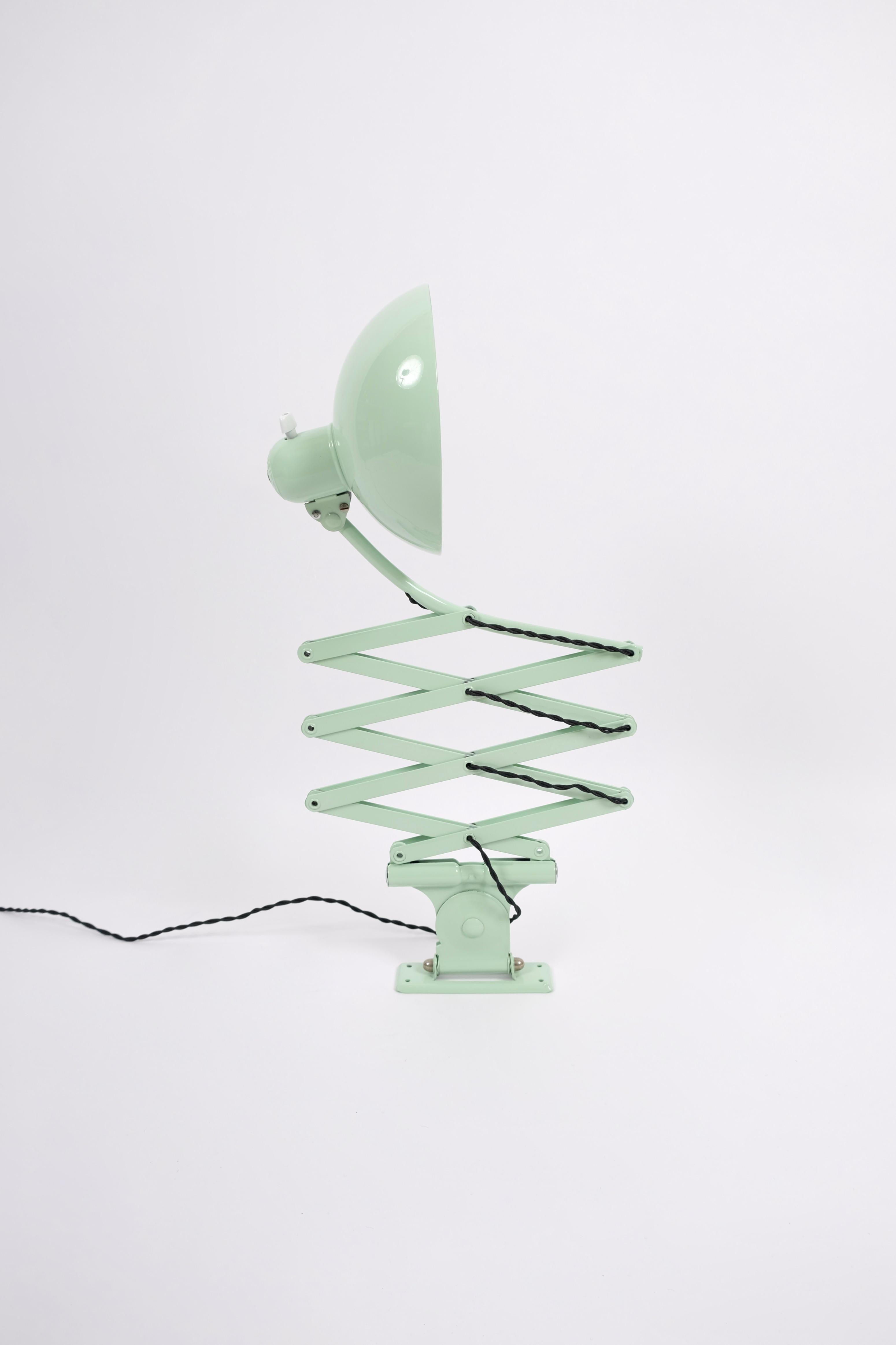 Scissor lamp proffesionally relacquered in pistacio green.
Designed in 1933 by the Bauhaus metal workshop head Christian Dell.
It can move in and out 50-110 cm.
The shade is mounted on a ball joint so that it can be adjusted up and down and side