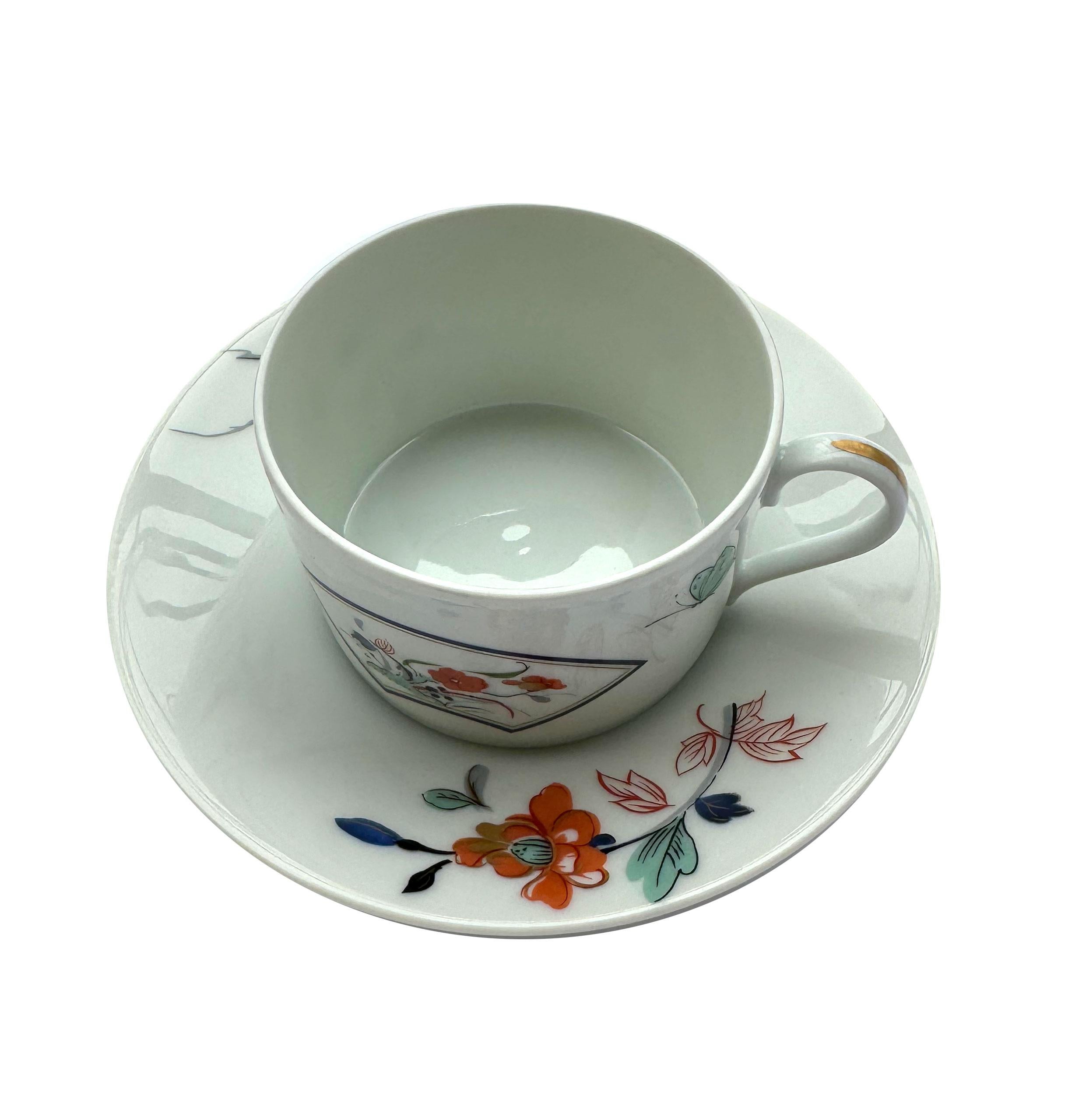 Porcelain cups and saucers designed by Christian Dior for Limoges, featuring a delicate Imari-inspired motif with floral and butterfly decorations. The design blends Japanese artistic tradition with French elegance, showcasing Dior’s refined