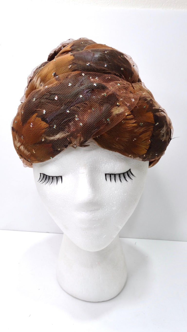 Amp up your accessory collection with this incredible vintage 1960's Christian Dior turban head piece! This wonderfully elegant and rare Christian Dior turban features a deep camel and brown color combination of feathers beneath a net dotted with