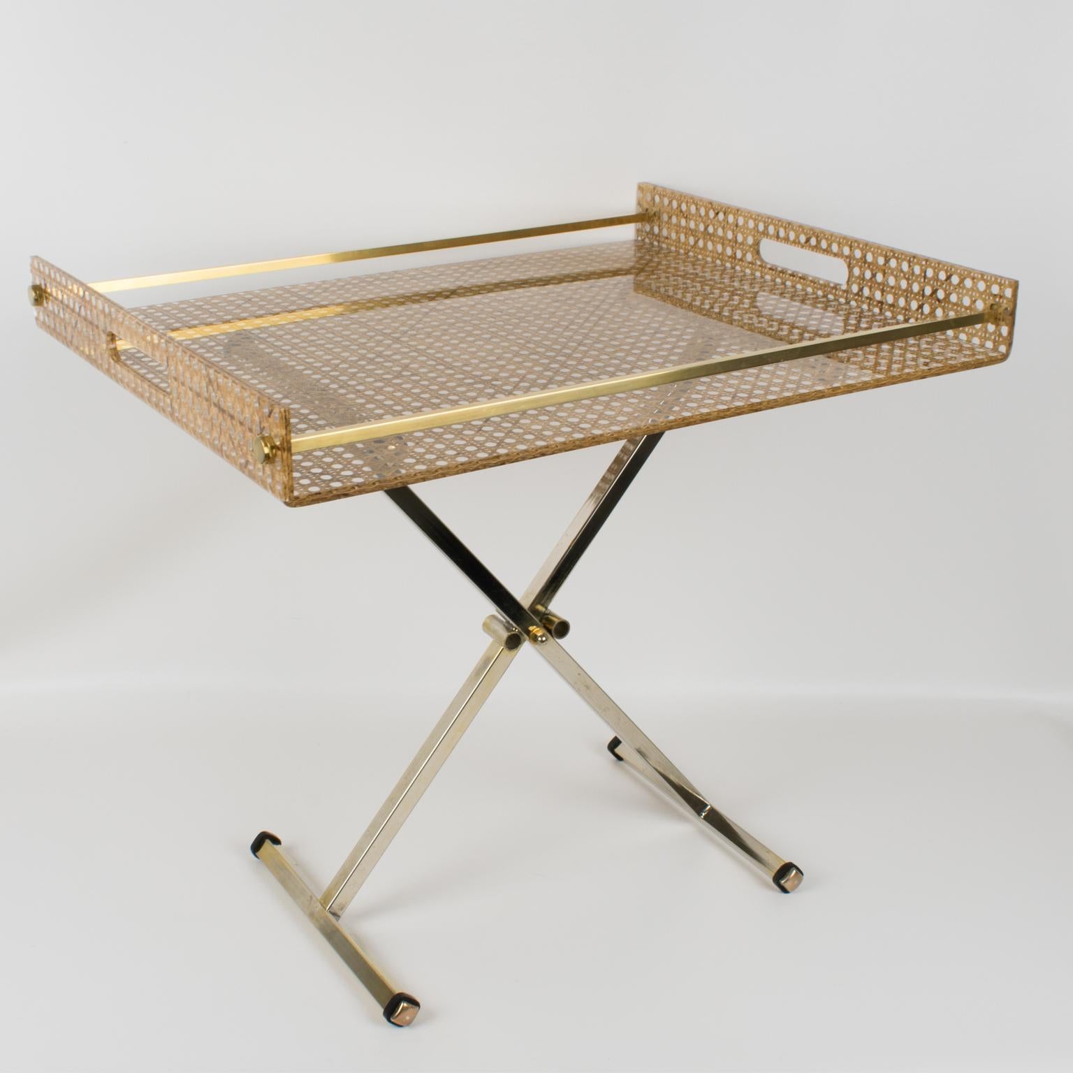 Elegant large barware folding tray table designed for Christian Dior Home Collection, in the 1970s. Rectangular butler shape with gilt brass gallery and real rattan cane-work or wicker embedded in the crystal clear Lucite. Gilded anodized metal